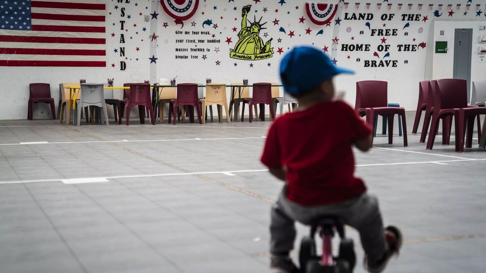 A migrant child is seen riding a tricycle in a border processing center.
