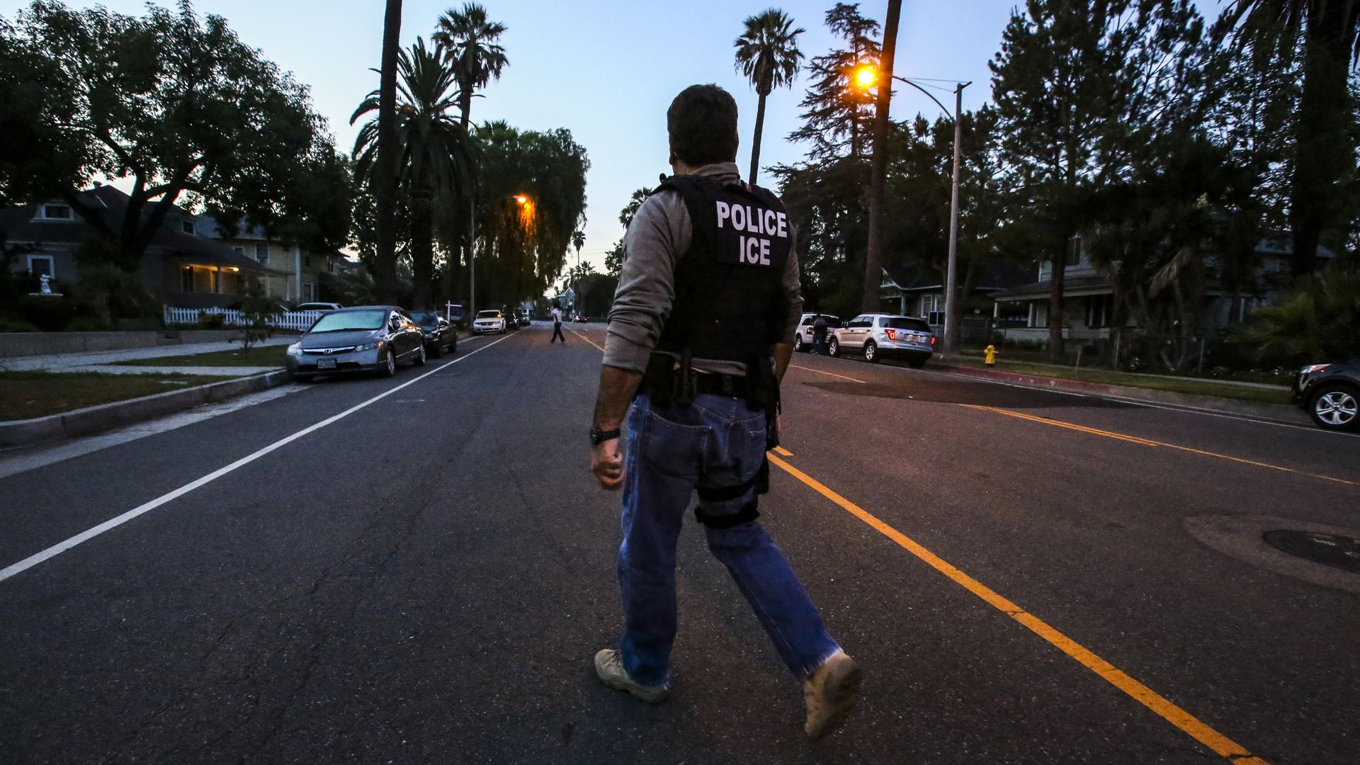 Ice officer walks down a street