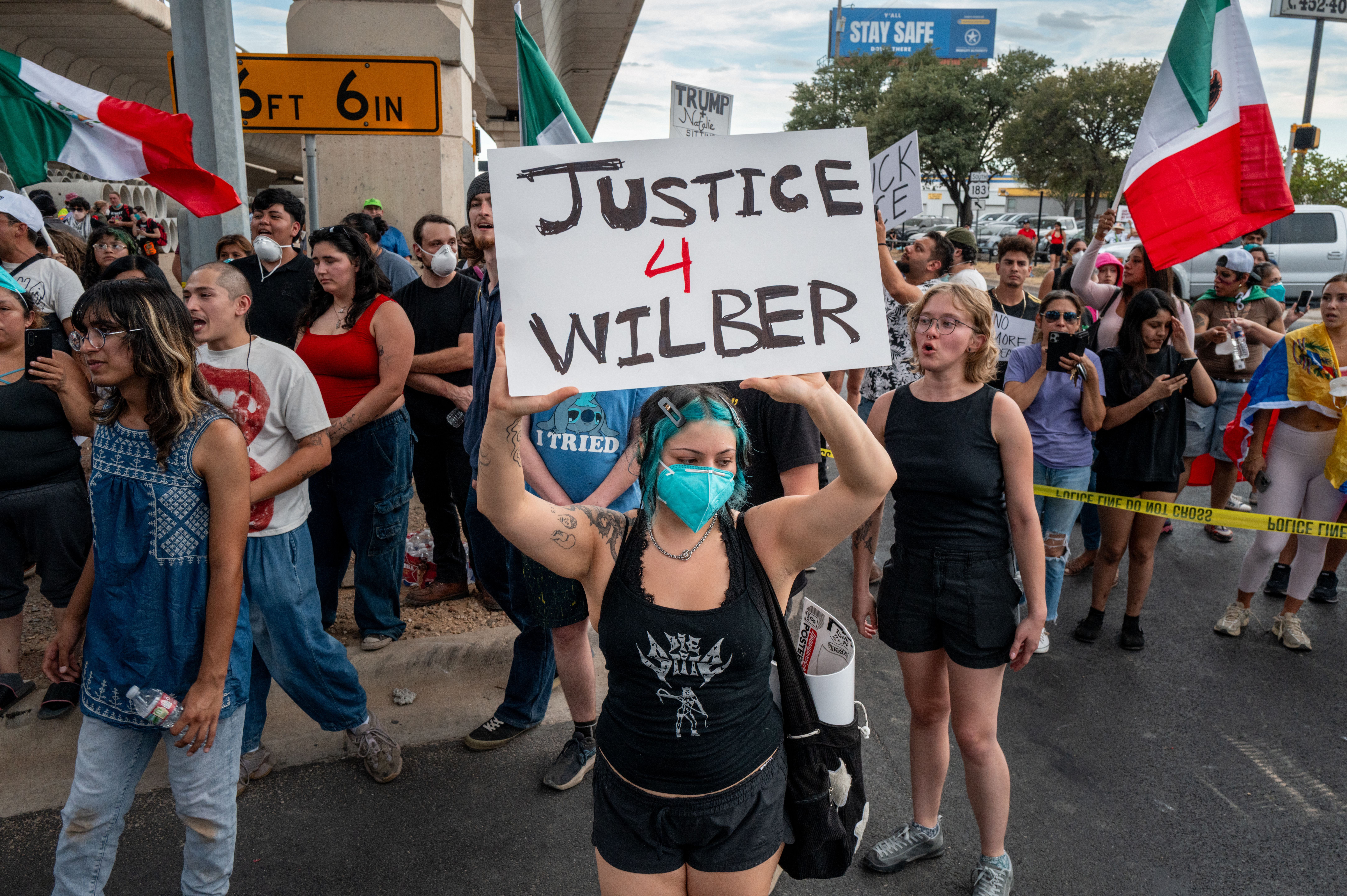 Protesters with signs gather at an intersection.