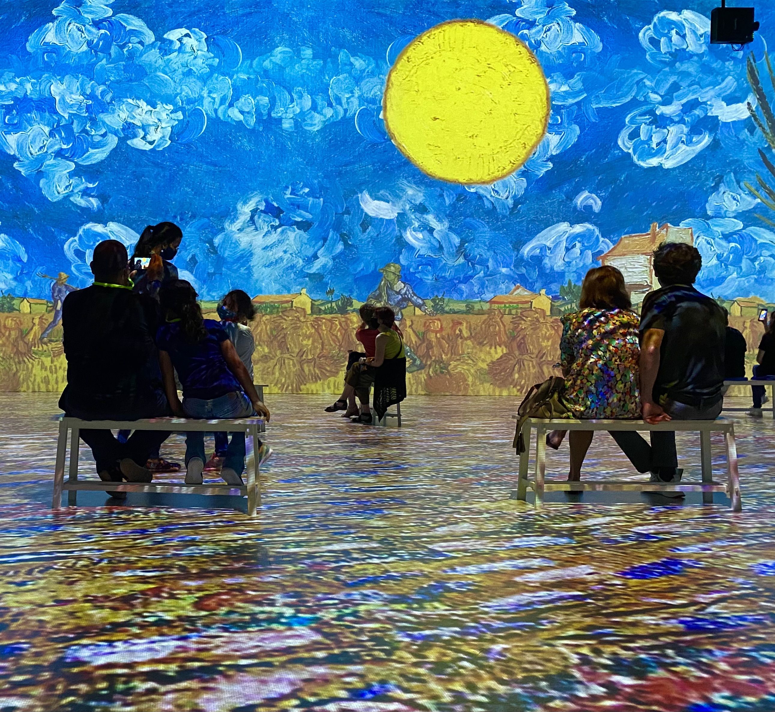 Spectators sit on benches at an impressive Van Gogh exhibition. 