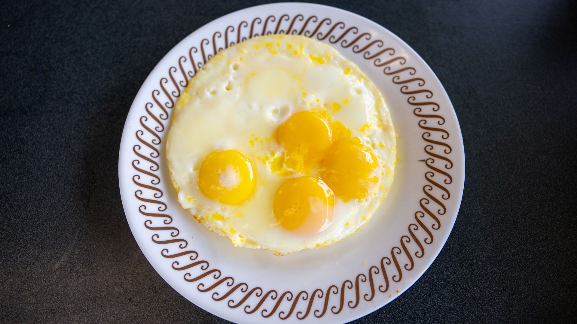 A serving of eggs placed on a plate with a brown loop design along the egde.