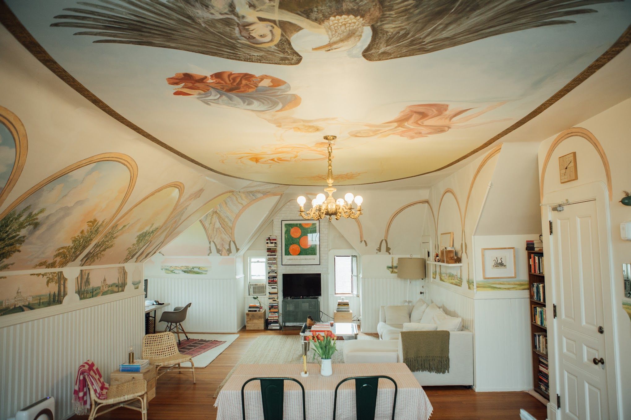 A photo of a living room with murals painted on the ceiling.