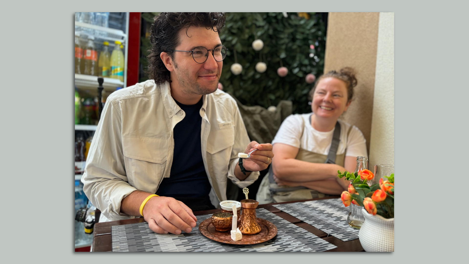 Author Sam Allard sits at table holding spoon with sugar cube with wife onlooking