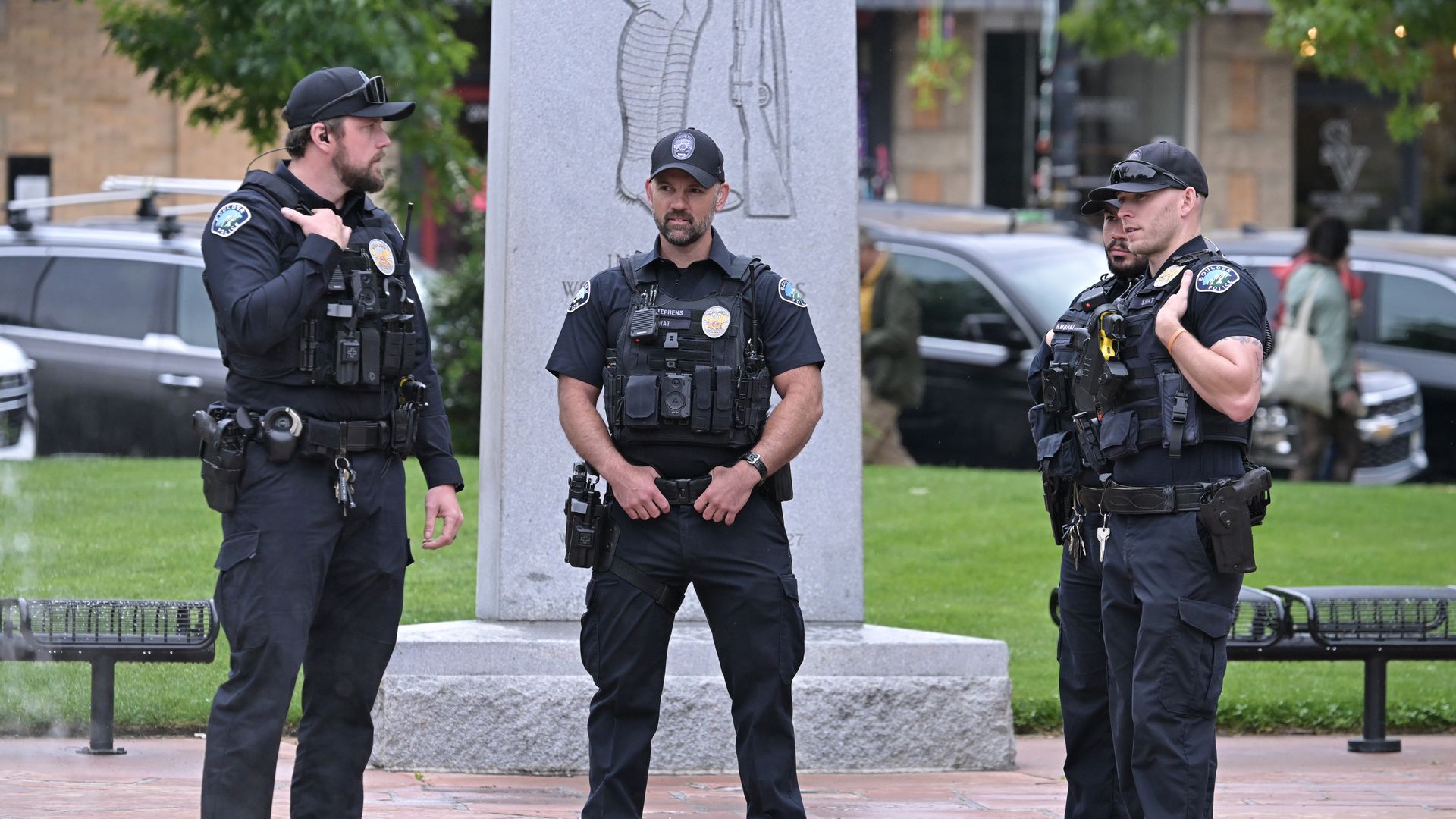 Three Boulder police officers stand outside the Boulder County Courthouse on Pearl Street.