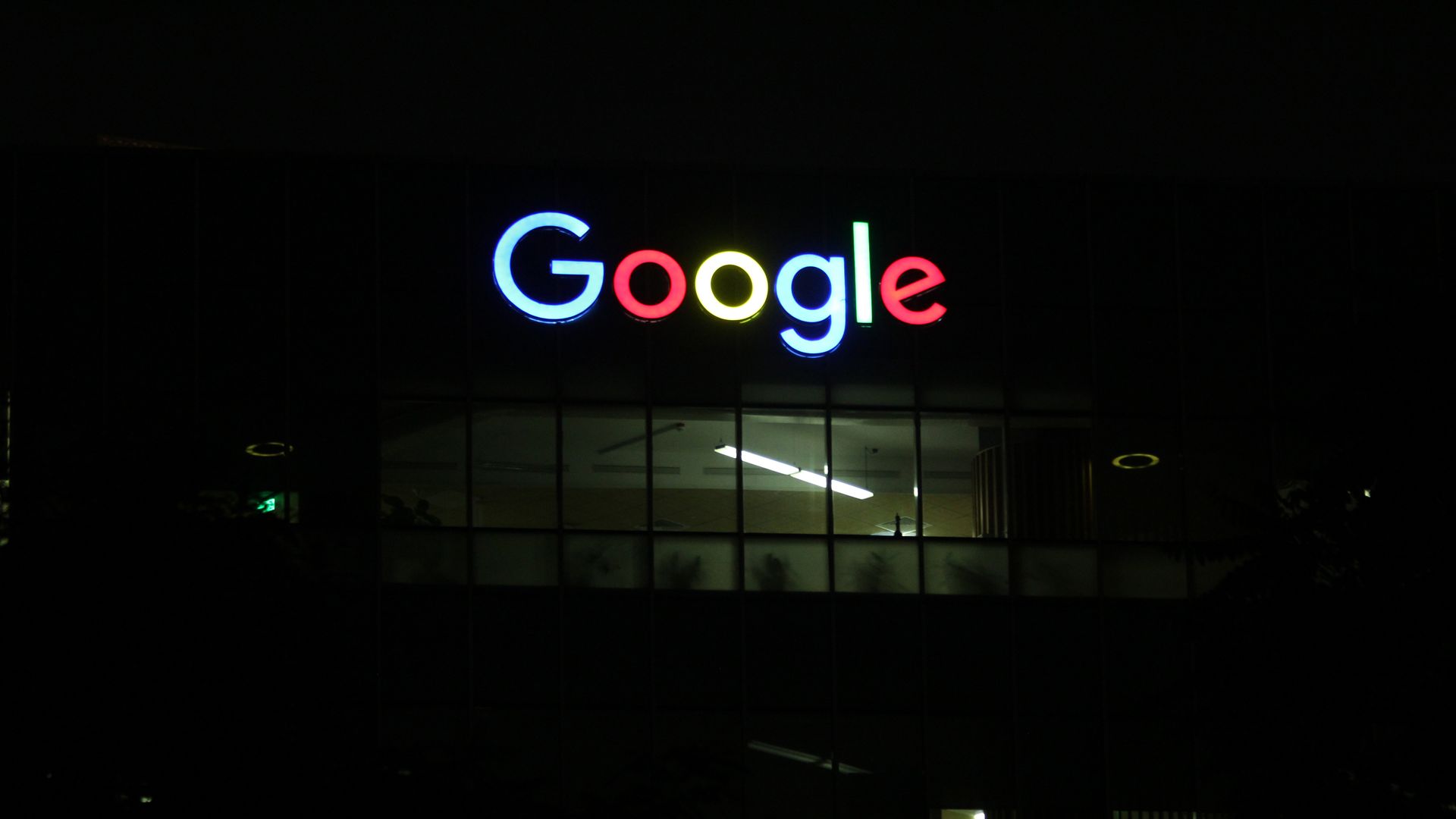 Google logo lit up outside building in the dark