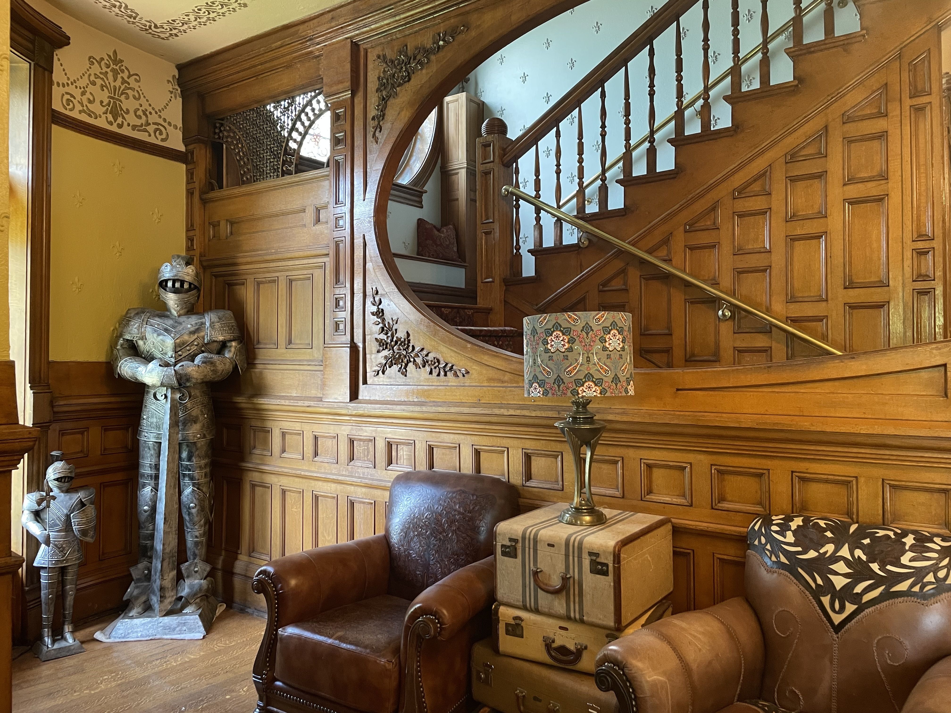 The inside of a castle in Denver showing knight armor next to wooden features and a staircase. 