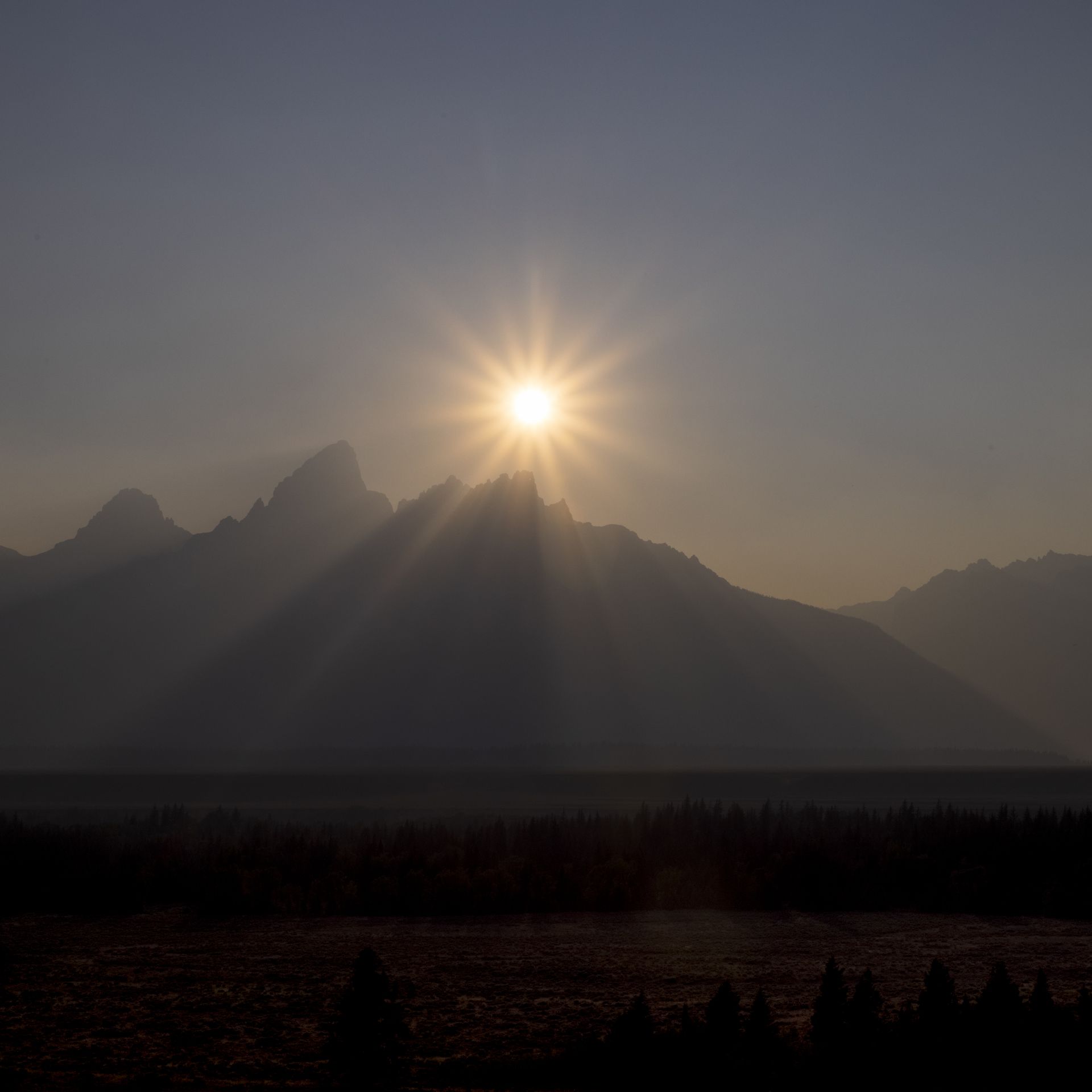 The sun sets behind the Grand Teton peak, shrouded in smoke from regional wildfires July 14, 2021 at Grand Teton National Park. 