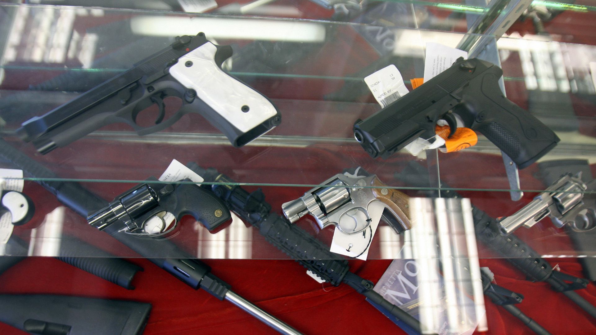 Several guns are shown under a glass case. 