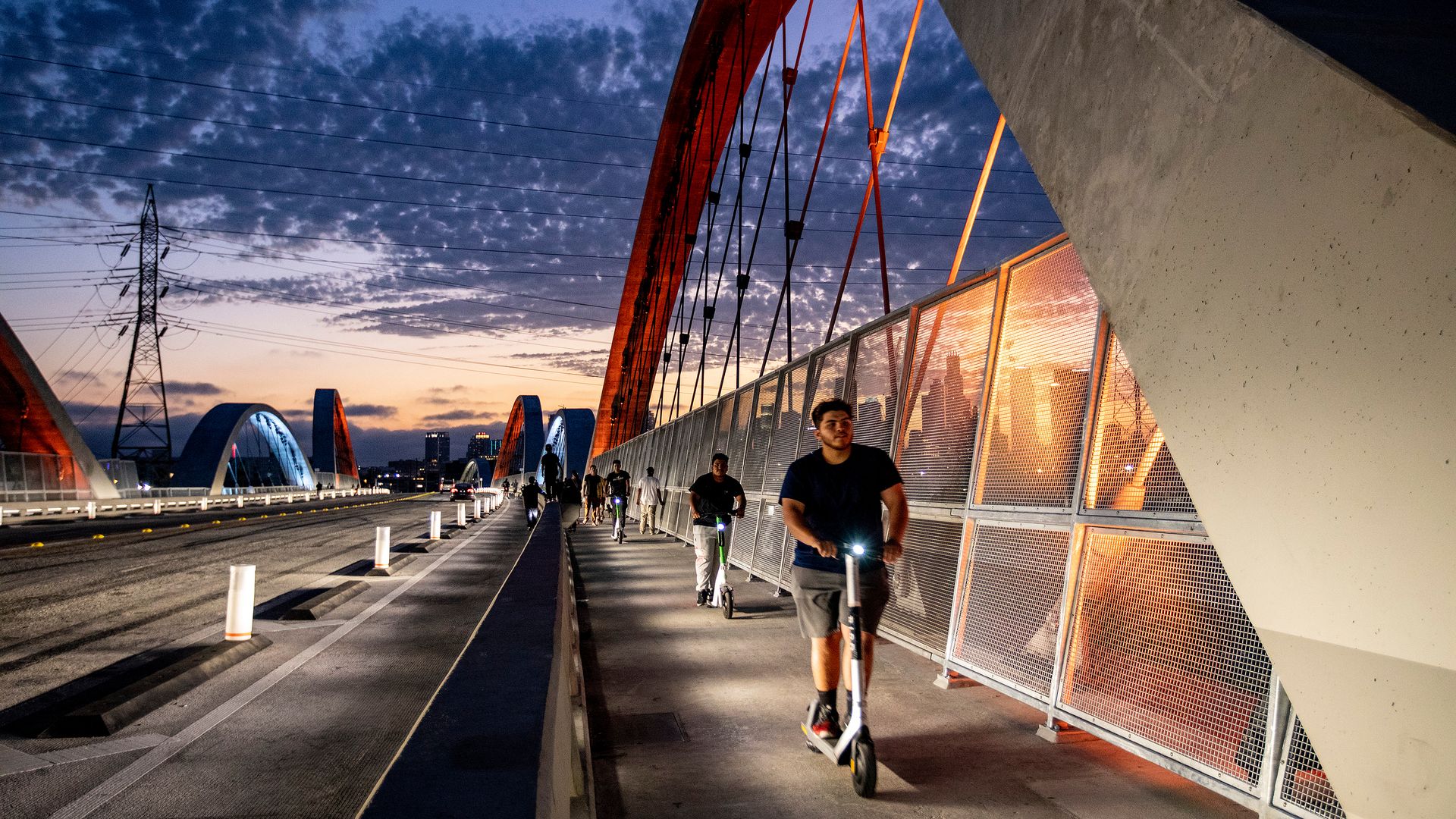 Pedestrians ride scooters on the Sixth Street Viaduct at dusk in Los Angeles, California, US, on Wednesday, July 27, 2022.