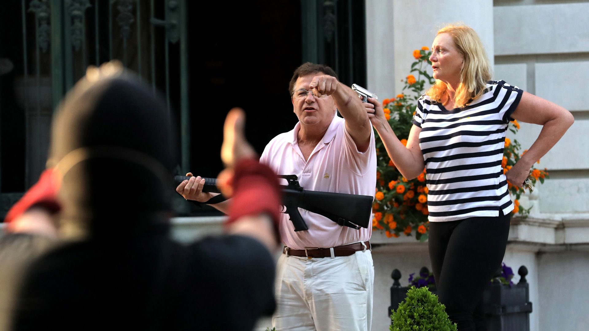 Armed homeowners Mark T. and Patricia N. McCloskey stand in front their house as they confront protesters marching to St. Louis Mayor Lyda Krewson's house on June 28, 2020.