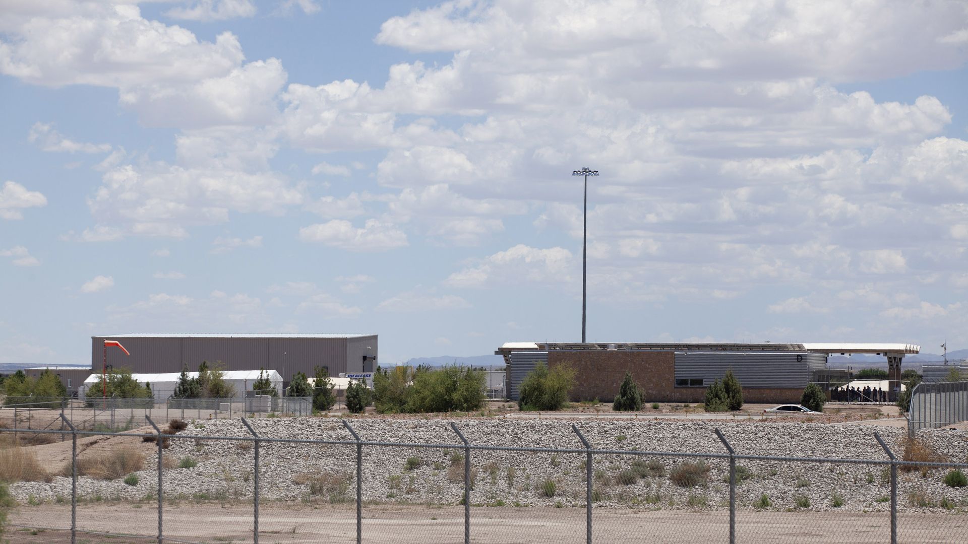 Tents being built behind a chain link fence to hold child migrants. 