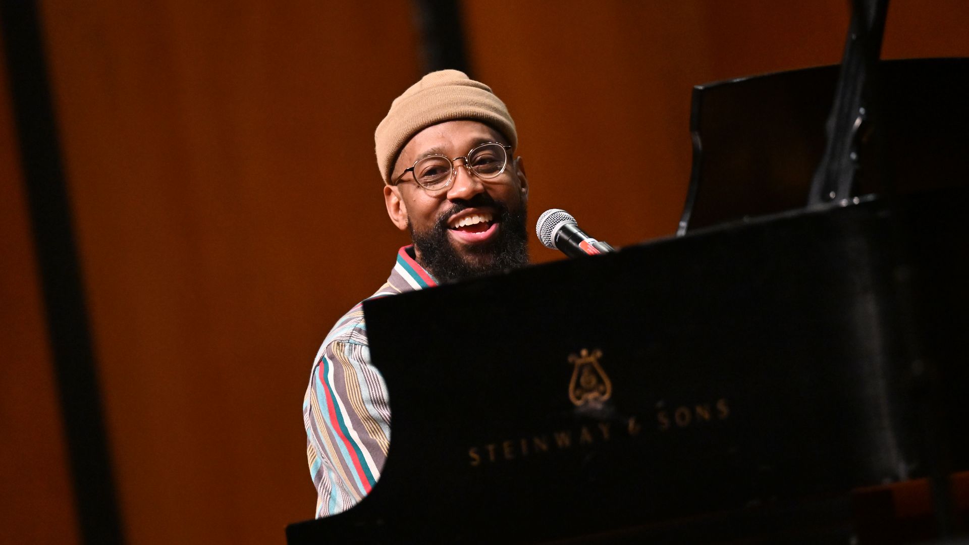 Image shows PJ Morton performing at a piano.