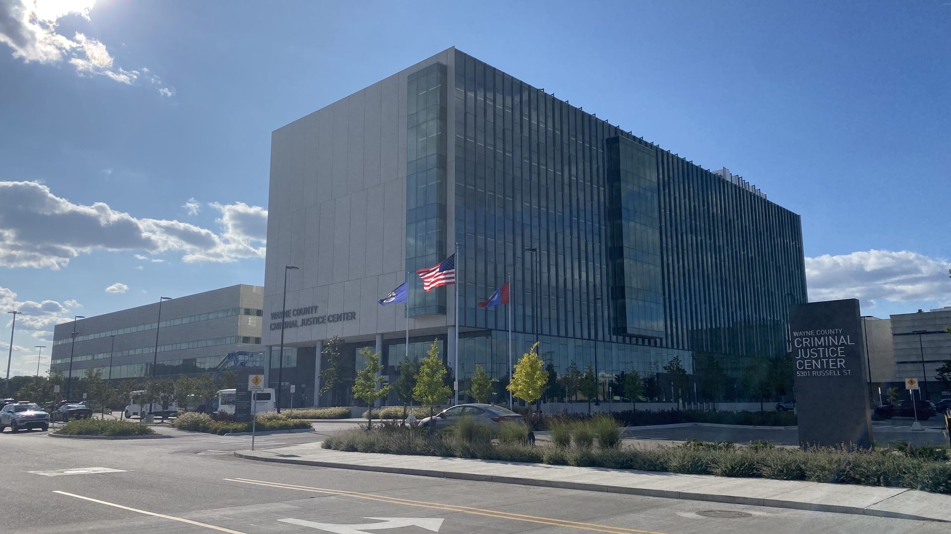 The criminal justice complex sits with a flag in front of it on a sunny day. 