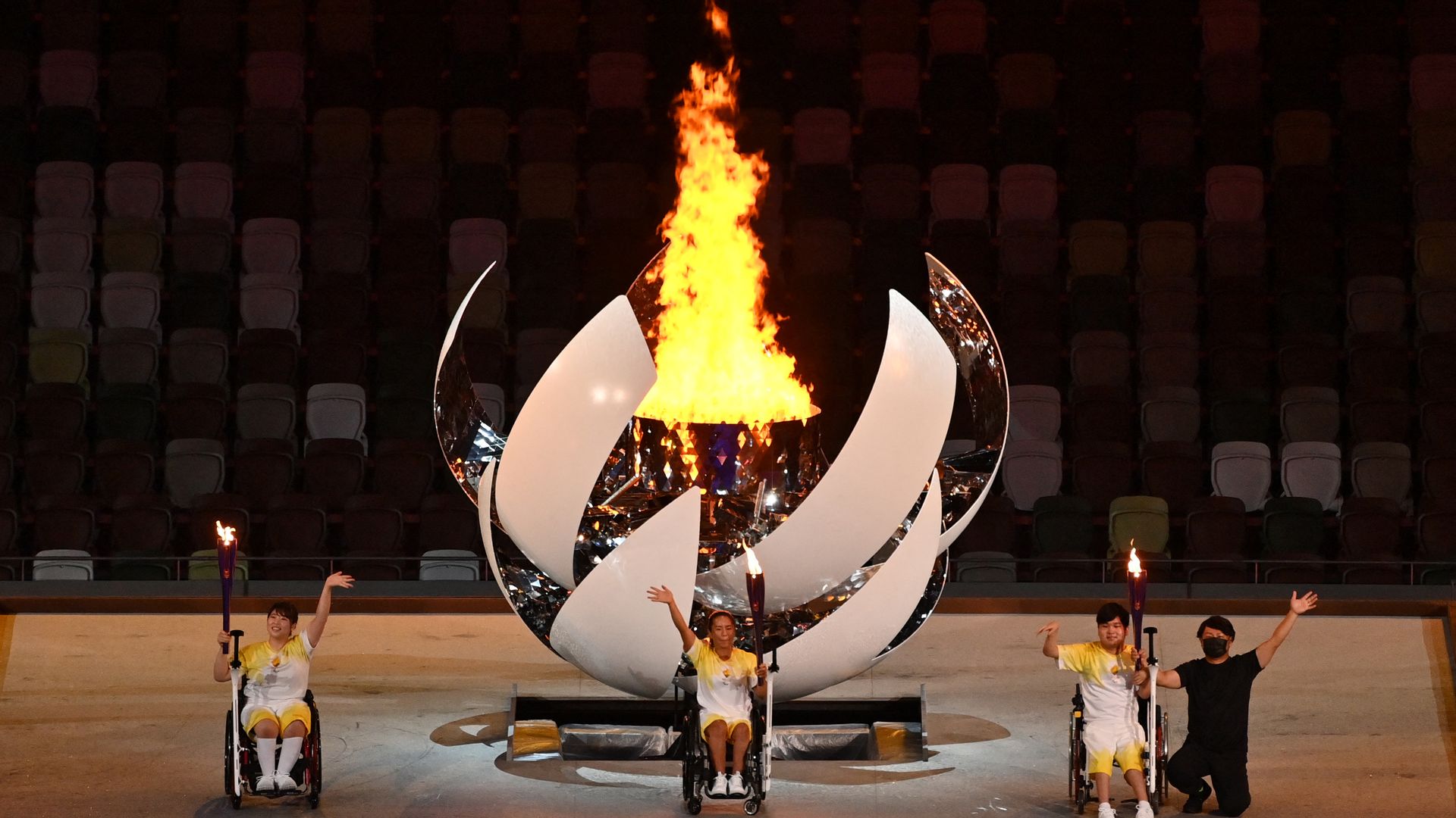 Three torchbearers wave after lighting the cauldron during the opening ceremony for the Tokyo 2020 Paralympic Games at the Olympic Stadium in Tokyo on August 24, 2021.