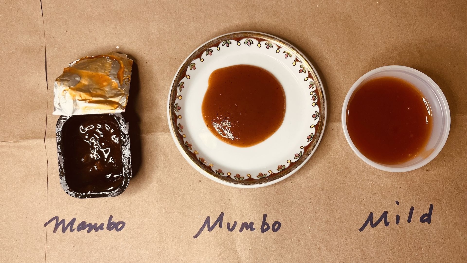 McDonald's BBQ sauce, next to plate of BBQ sauce, next to plastic cup of BBQ sauce, all sitting on brown paper bag.