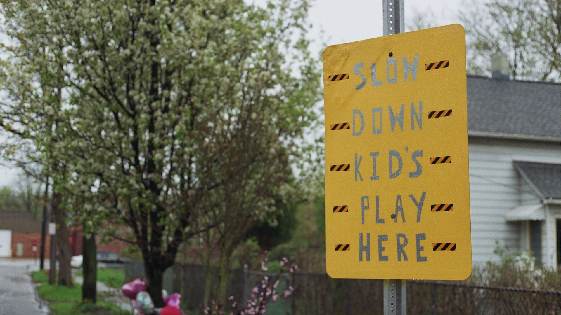 A handmade yellow street sign advising motorists, "Slow down, kids play here."