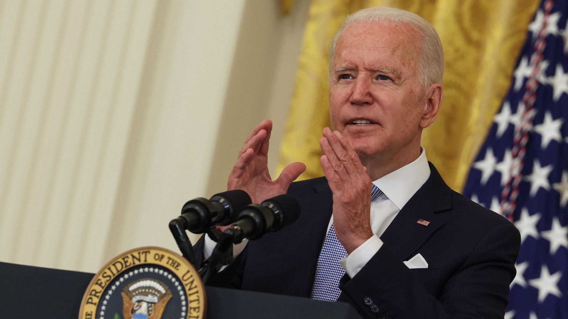 Picture of President Biden speaking behind a podium gesturing with his hands in front of him
