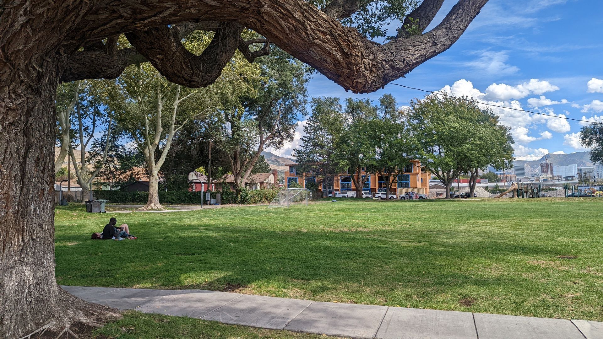 A couple picnics in the shade at Madsen Park while new apartments are under construction across the street.