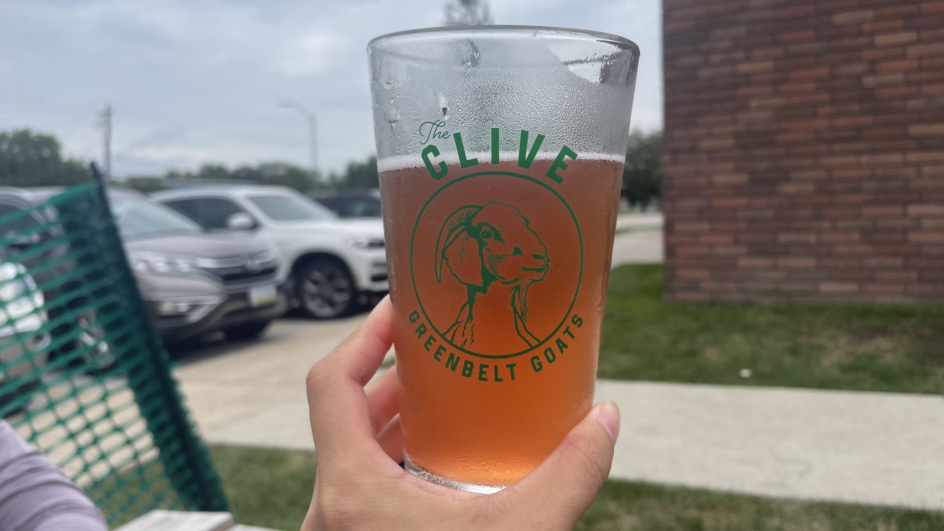 A hand holds a beer with the Clive Greenbelt Goats.