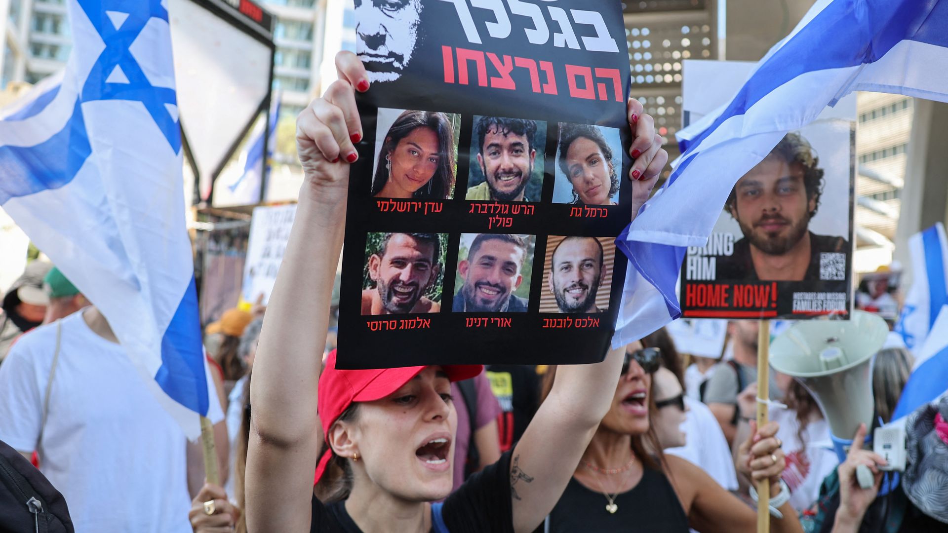 A protester lifts a placard bearing portraits of six Israeli hostages whose bodies were recovered by the army from the southern Gaza Strip, during a rally by families and supporters of the hostages in Tel Aviv on September 2, 2024, 