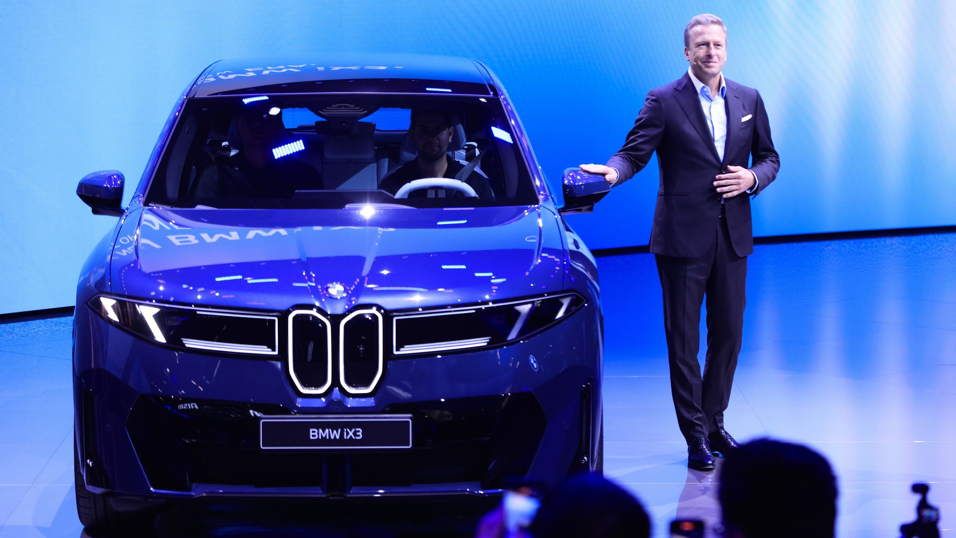 Photo of Oliver Zipse, chief executive officer of BMW, on stage next to a blue BMW  iX3 Neue Klasse vehicle as the car is being introduced at the IAA Mobility 2025 expo in Munich, Germany.