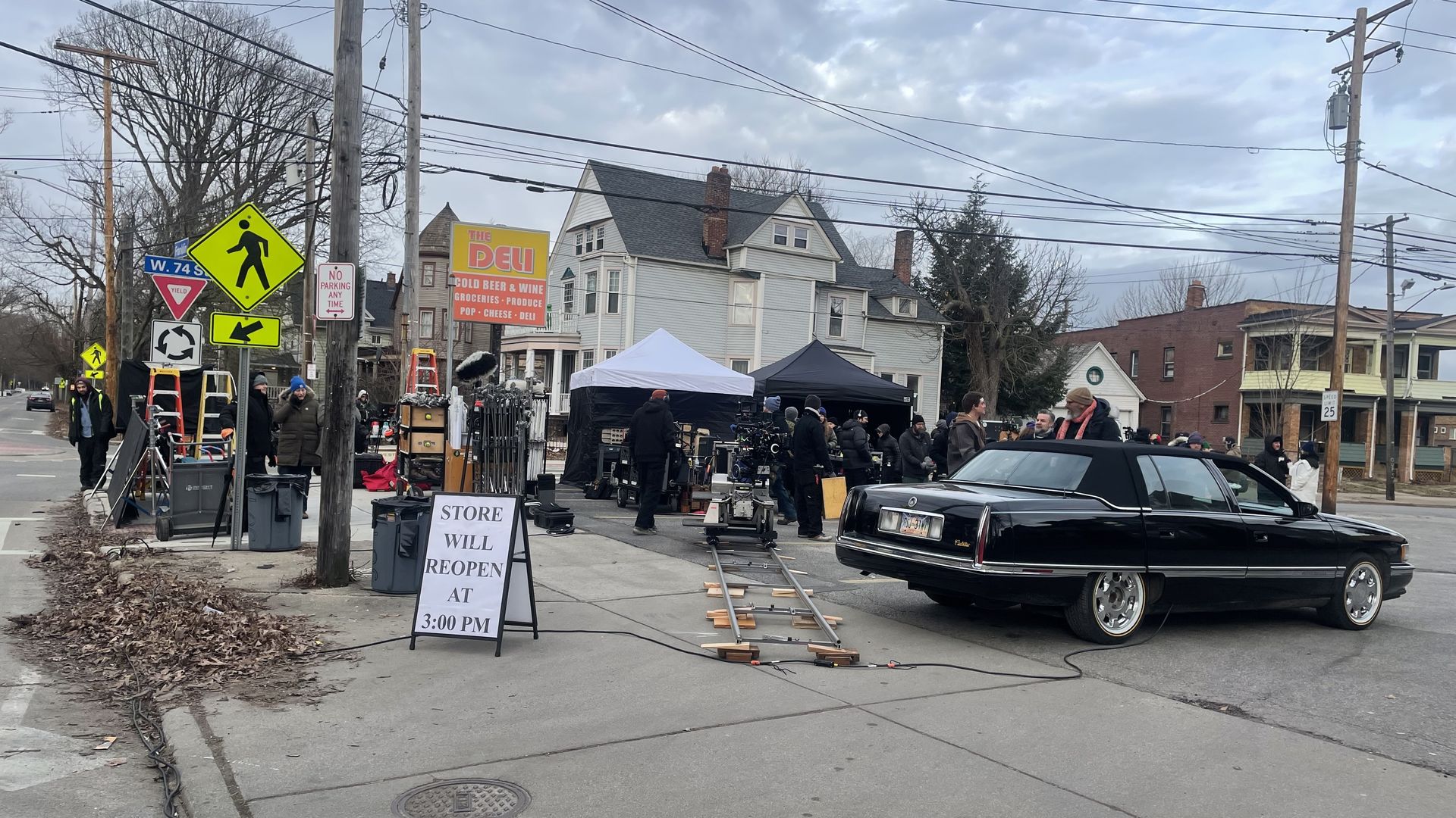Film crews at corner store with black car in parking lot
