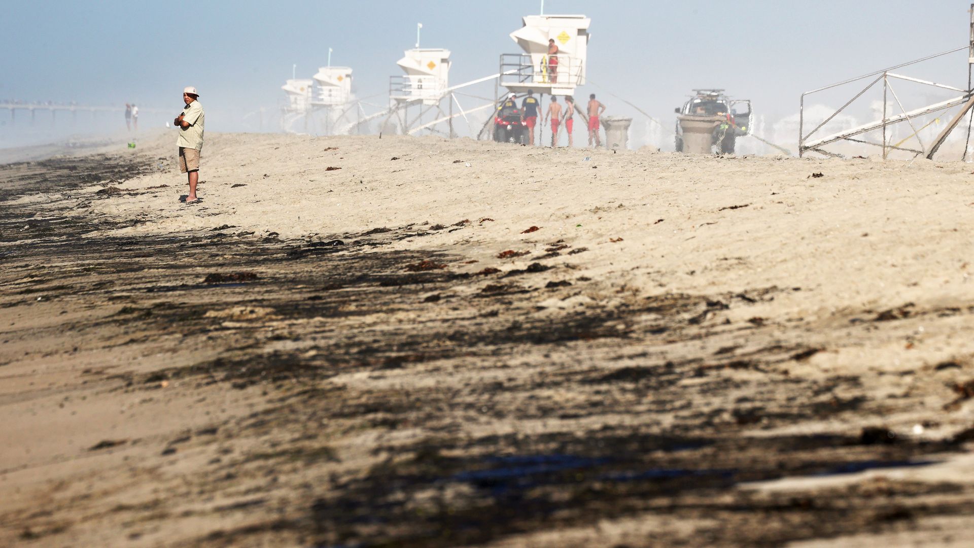 A person stands near oil washed up on Huntington State Beach after a 126,000-gallon oil spill from an offshore oil platform on October 3, 2021 in Huntington Beach, California