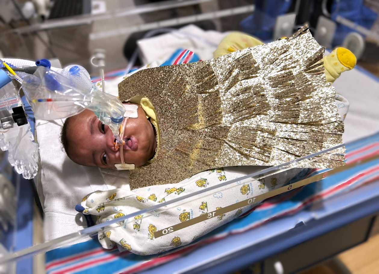Photo shows a baby in a gold dress.