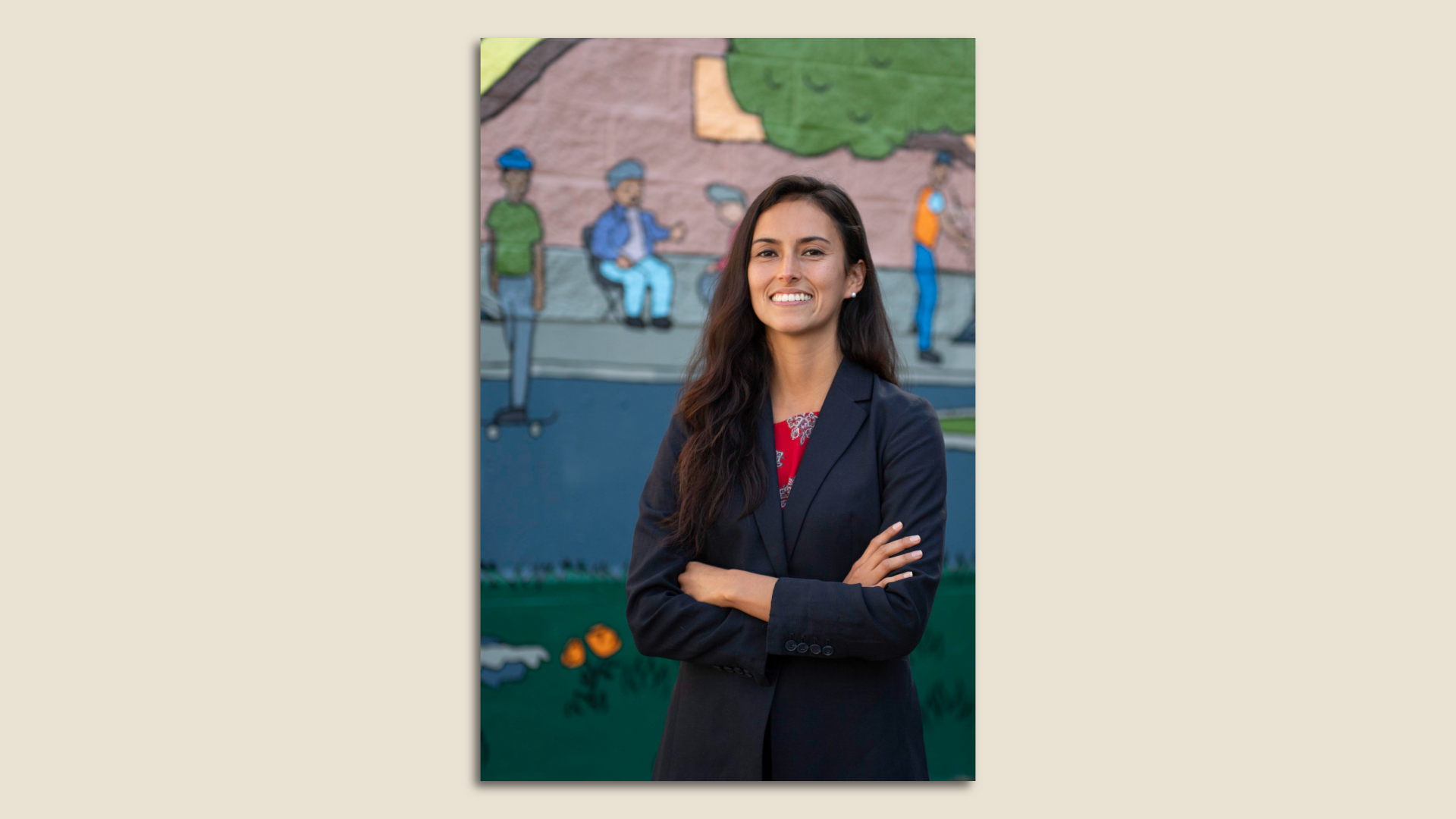 Photo of Jackie Fielder standing with her arms crossed next to a mural