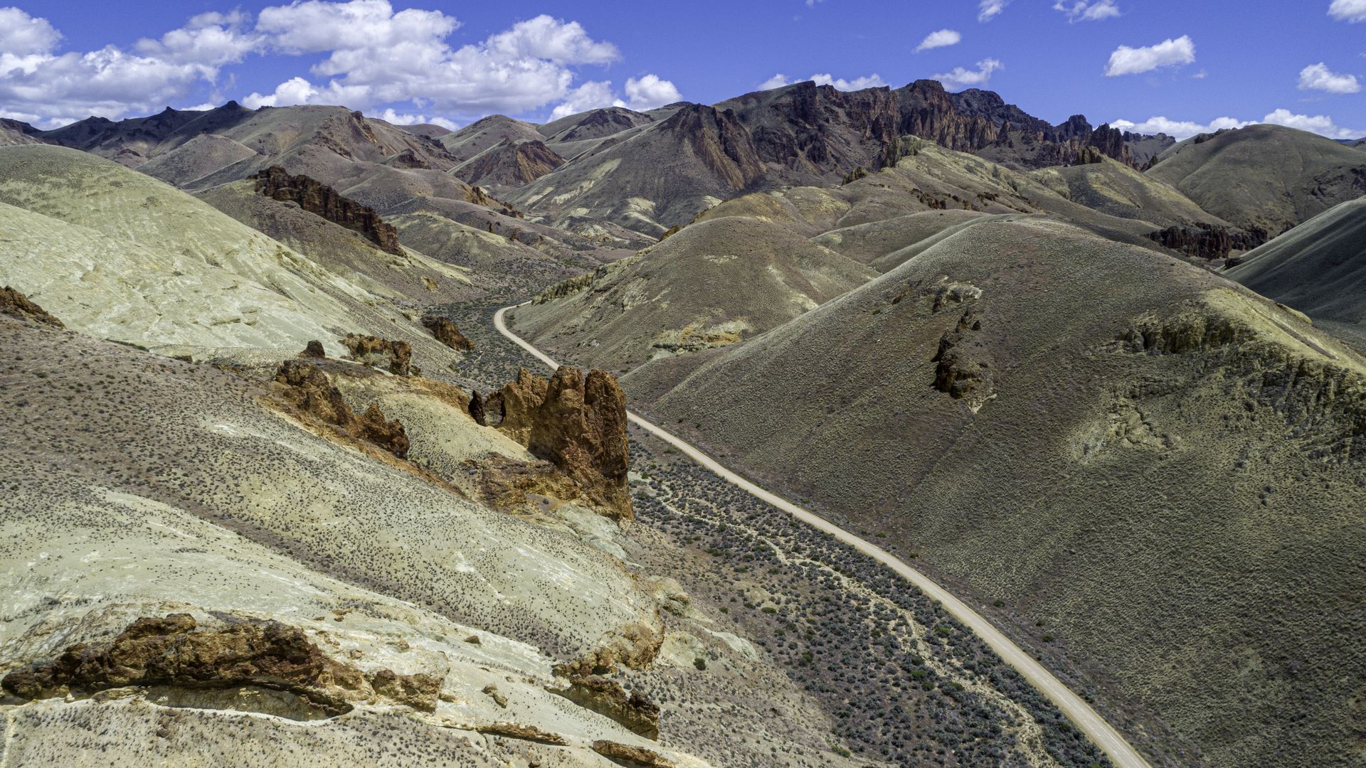 A photo of a valley, with red rocks and a two-track lane down the middle.