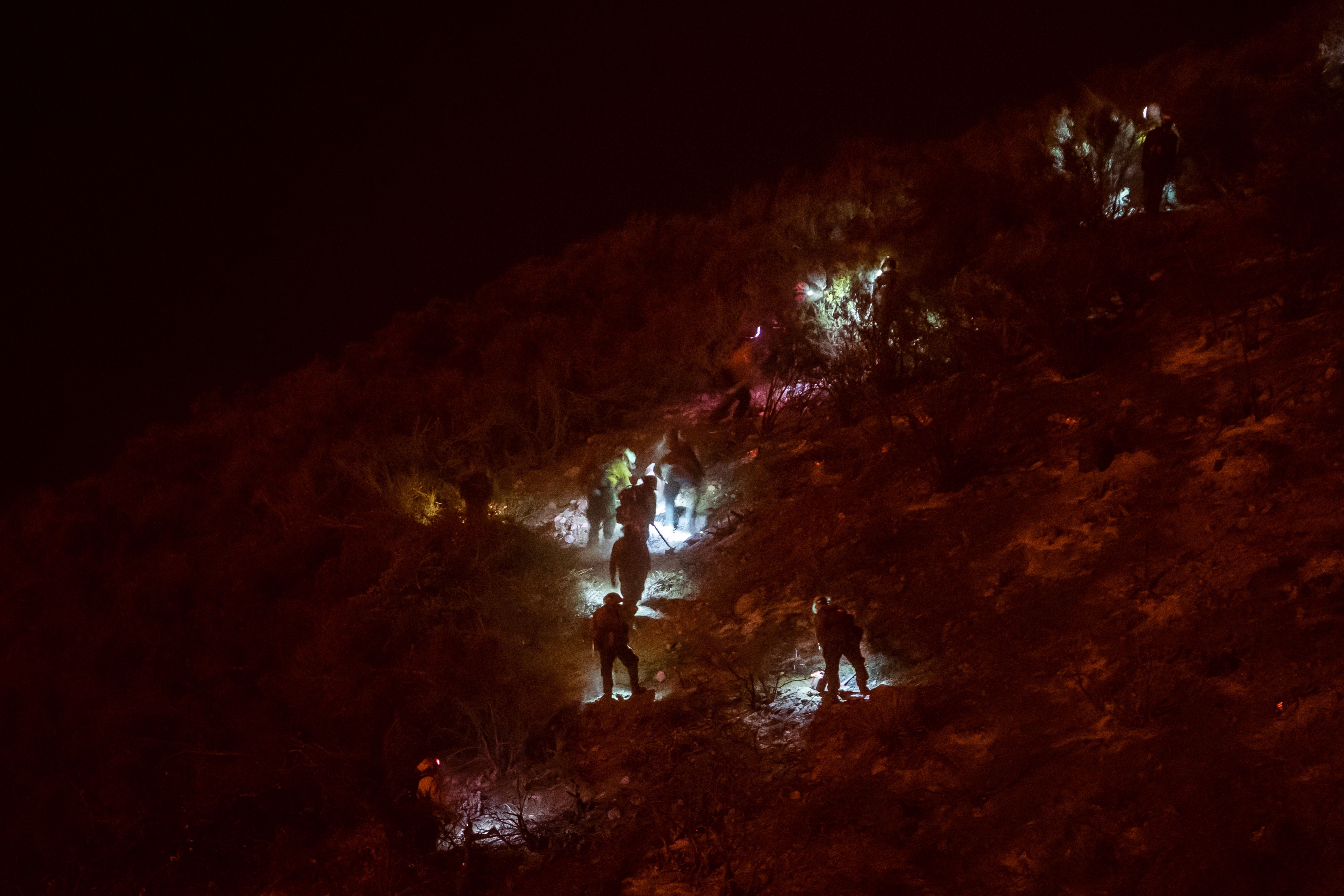 Firefighters work at night cutting trees and removing vegetation in order to make a firebreak as they battle the Lake Fire 
