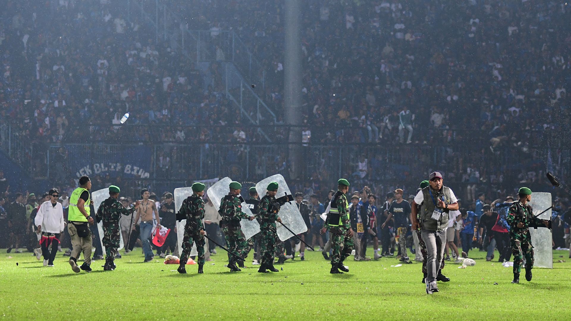 Members of the Indonesian army securing the pitch after a football match between Arema FC and Persebaya Surabaya at Kanjuruhan stadium in Malang, East Java. 