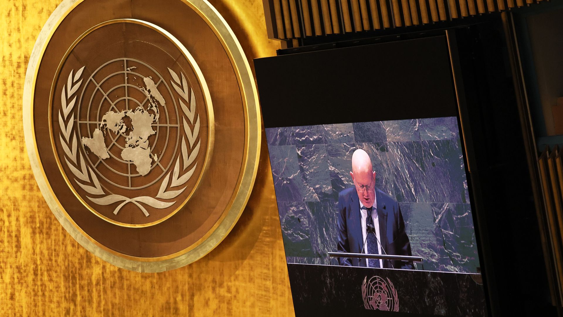Photo of the UN seal next to a screen showing a person speaking