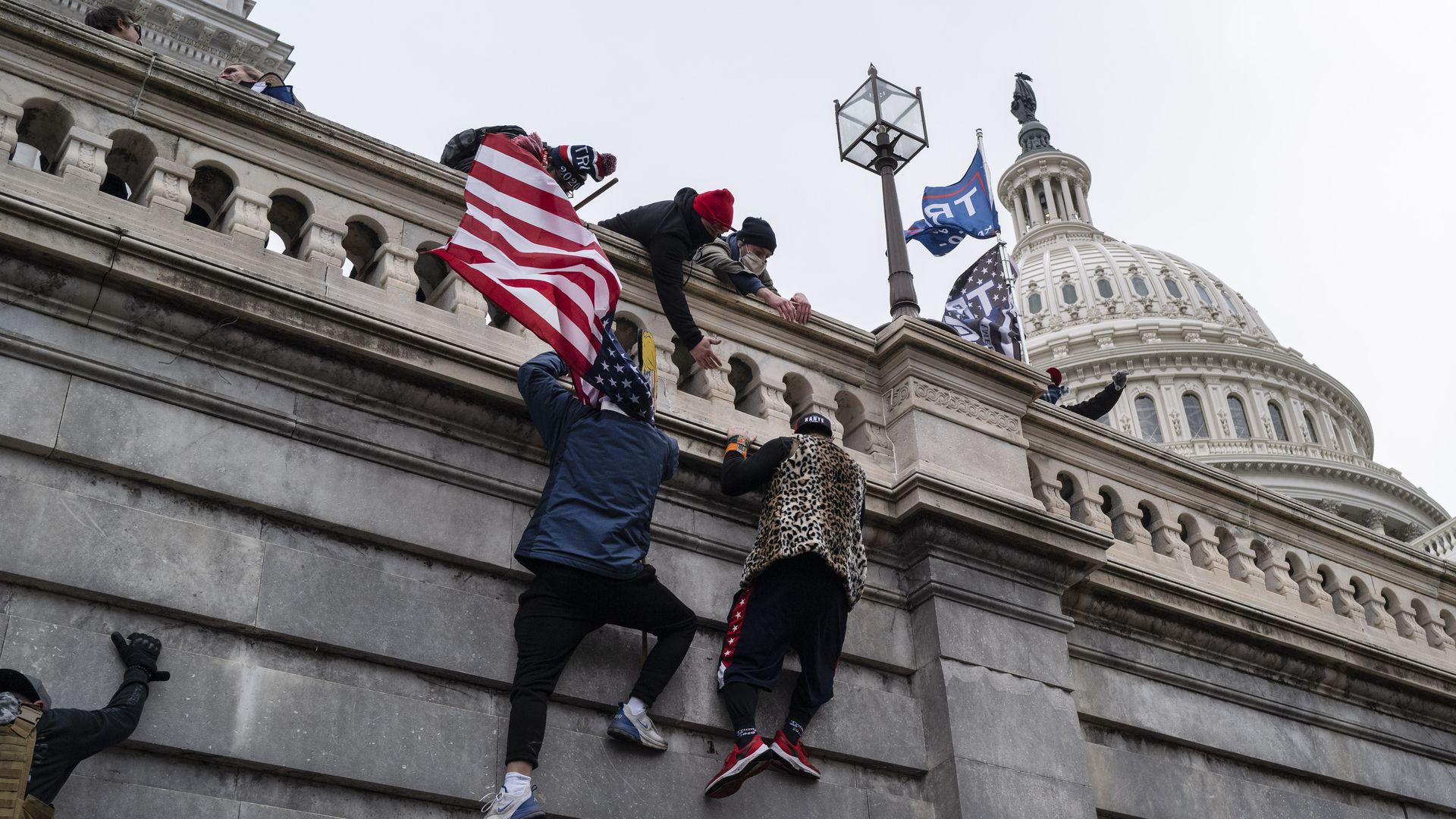 Photo of people scaling the wall of the U.S. Capitol building