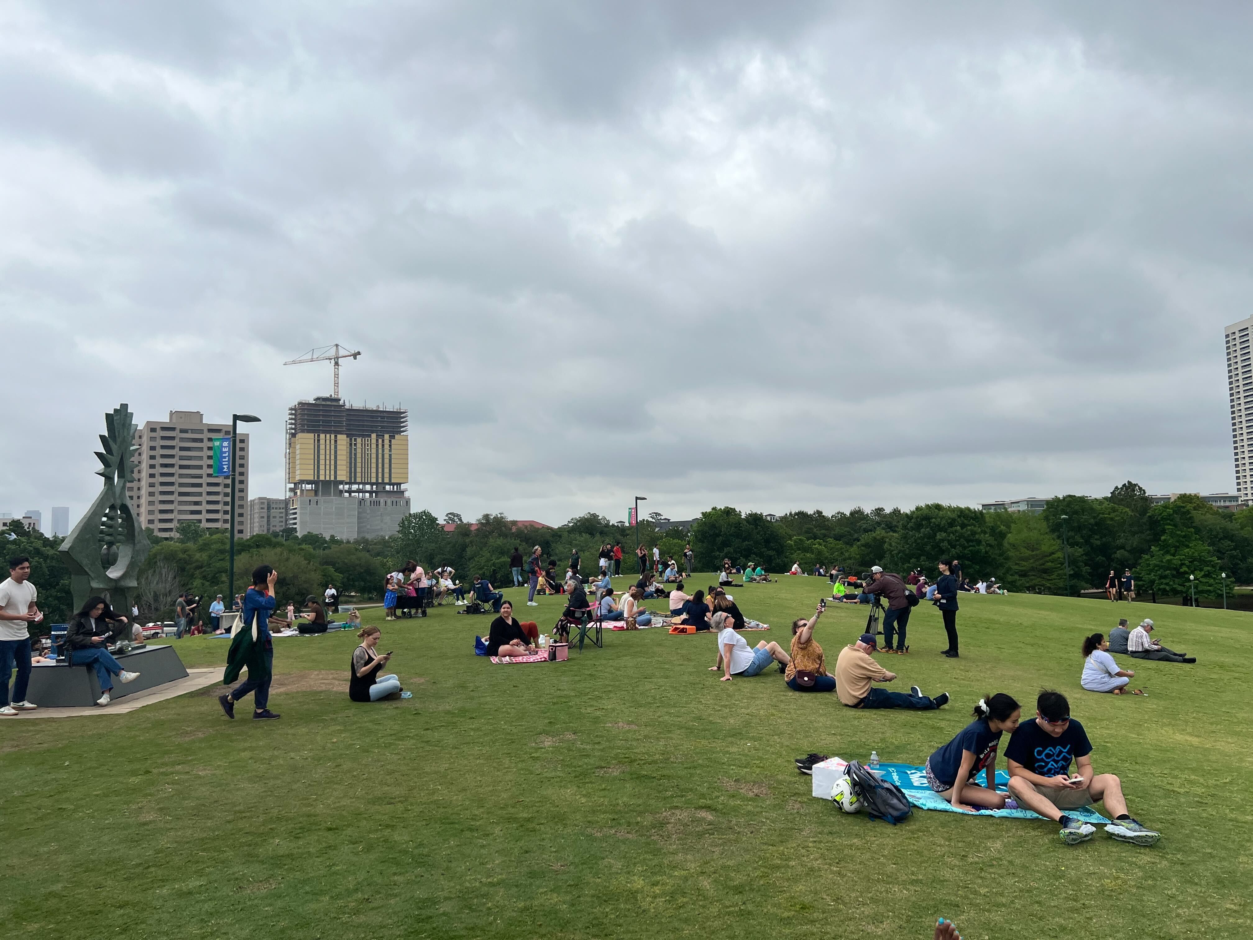People spread across a lawn under a cloudy sky