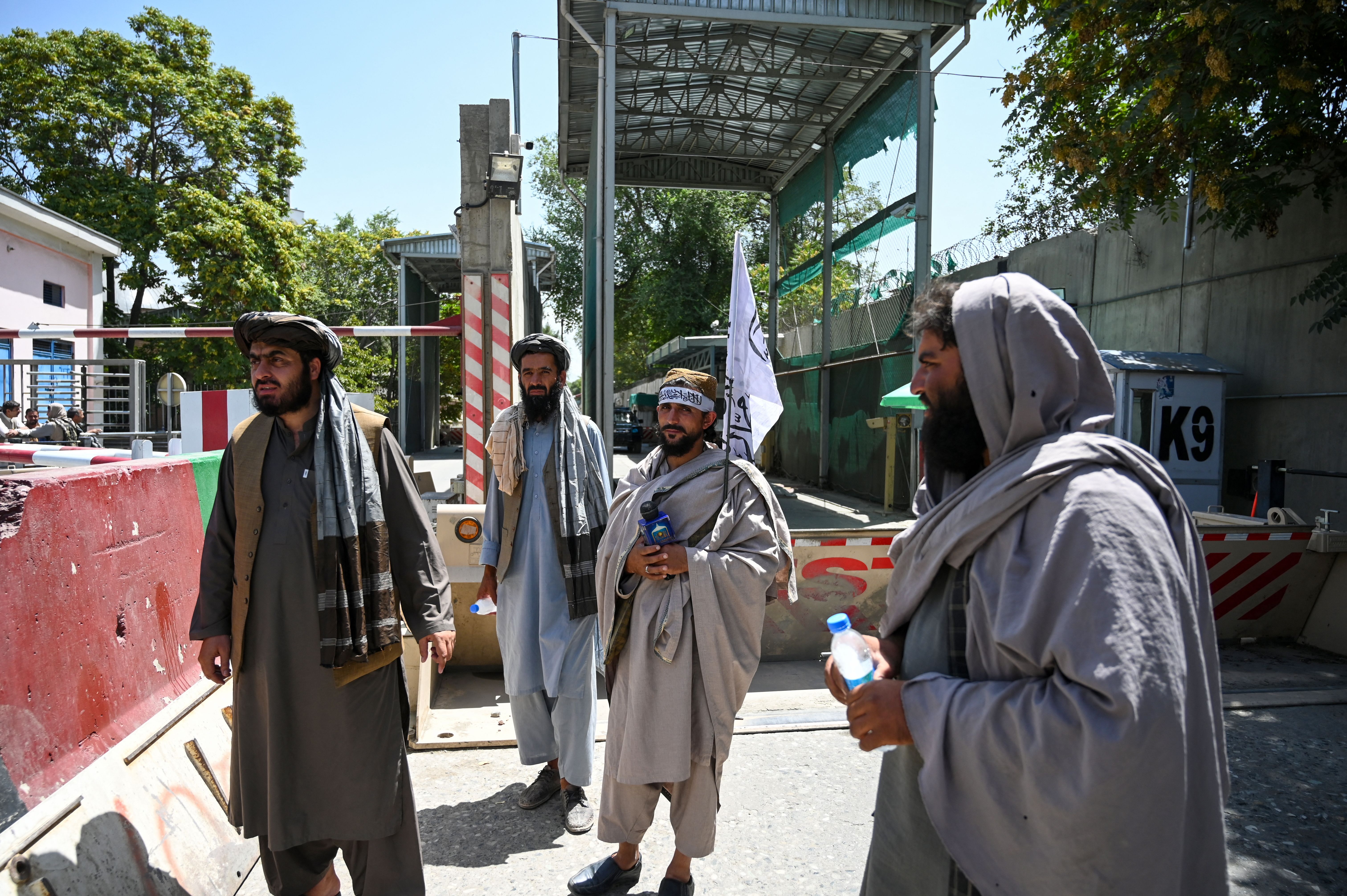 Taliban fighters stand guard at an entrance of the green zone area in Kabul on August 16