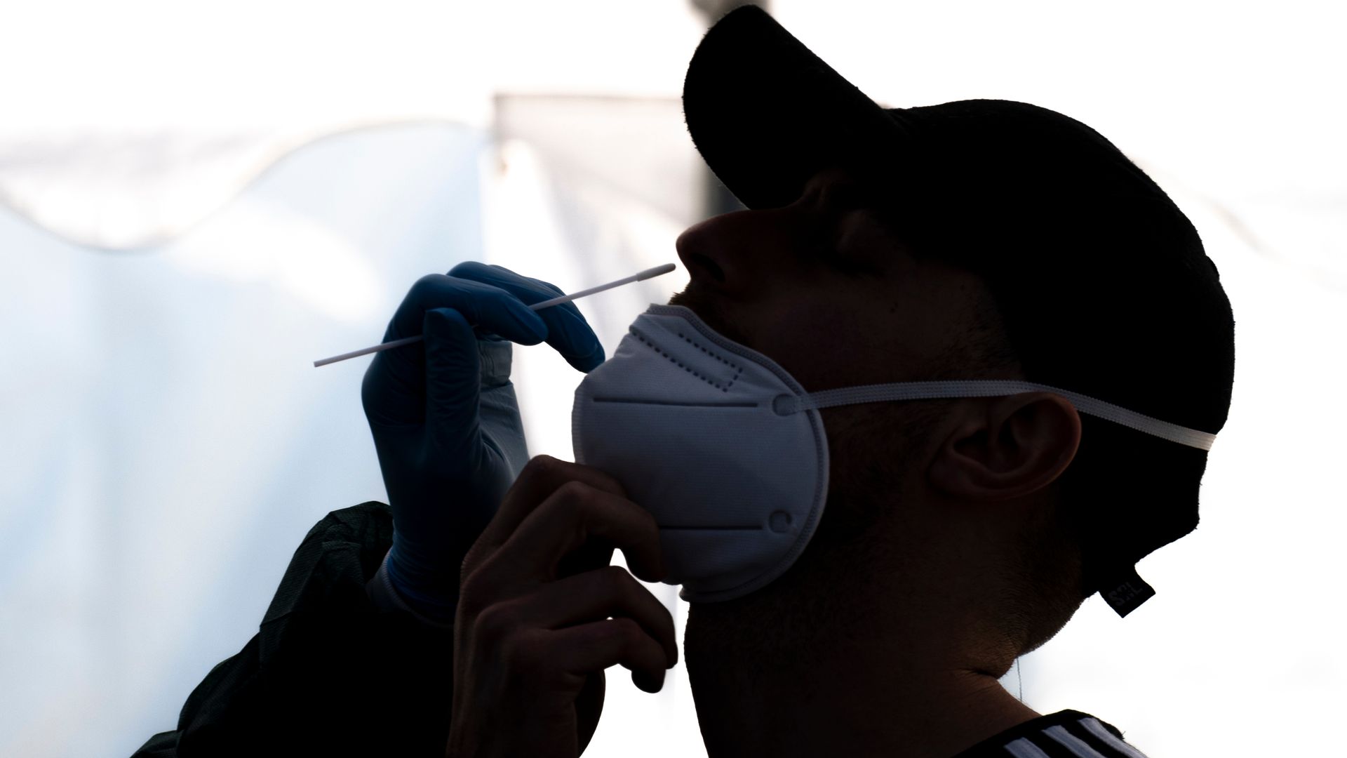 Photo of a person's head raised with a cotton swab held next to their nostril