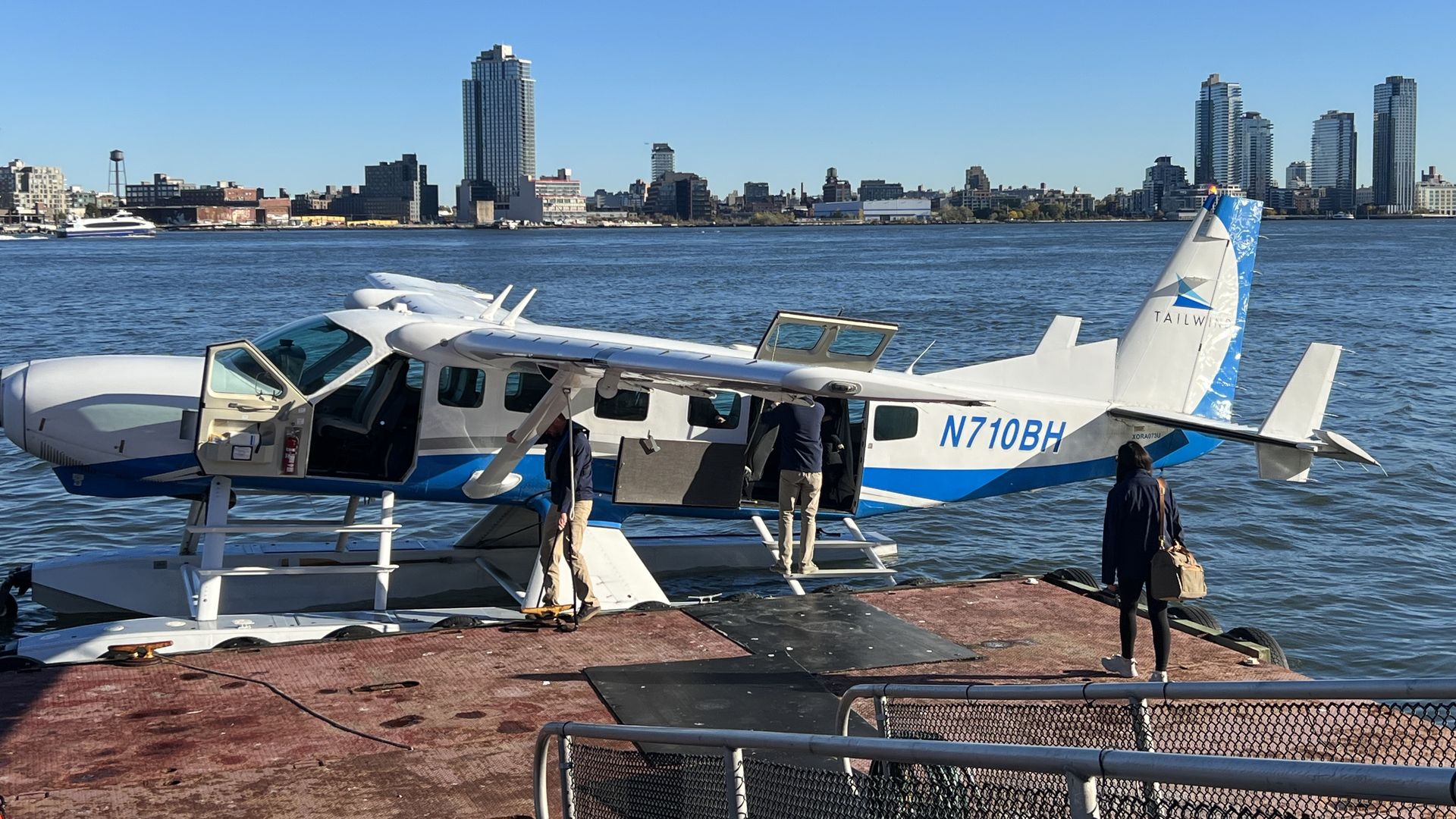 A Cessna Caravan seaplane docked on the East River as pilots prepare for passengers to board.