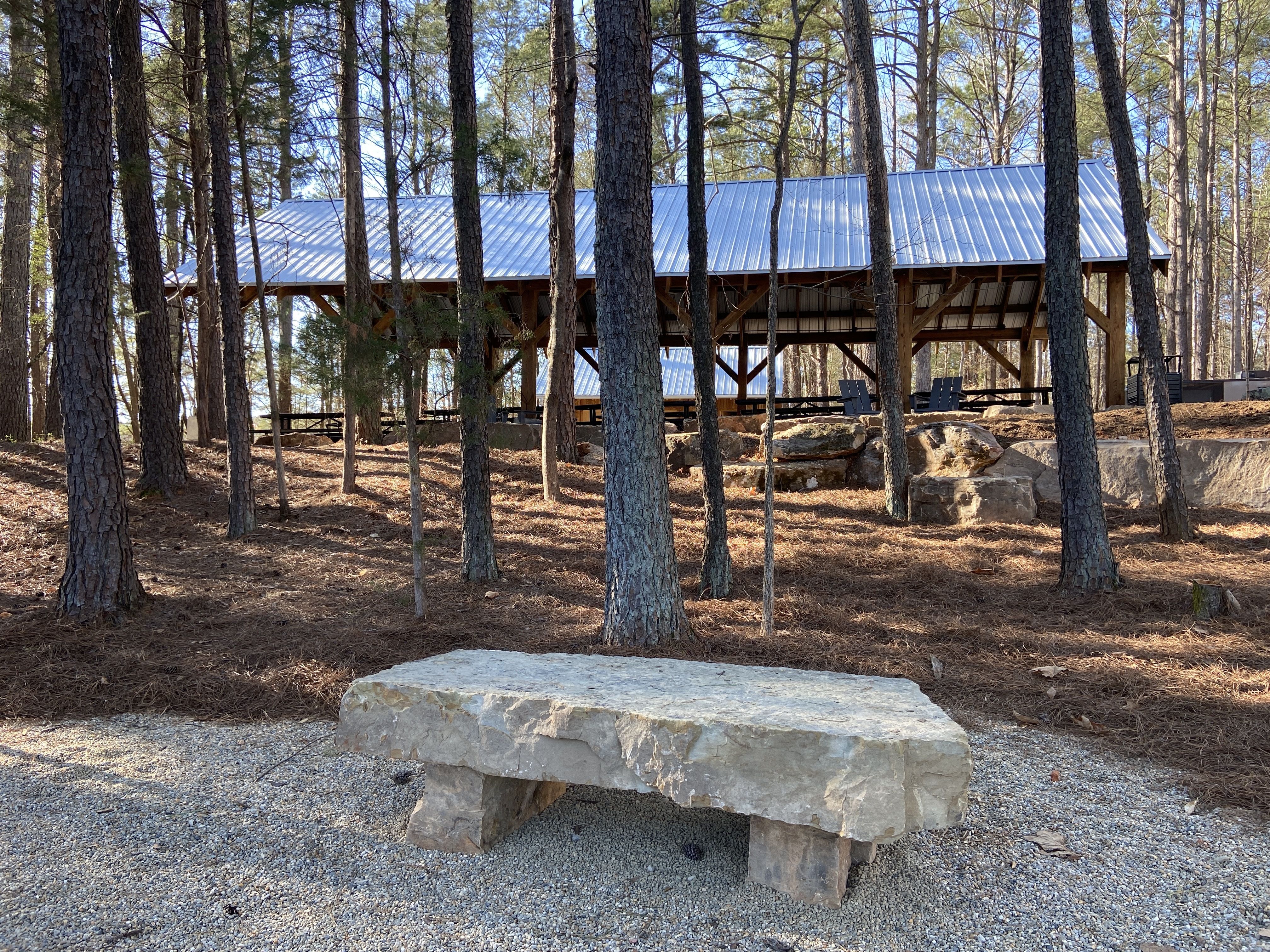 A stone bench surrounded by trees just down from the picnic area.