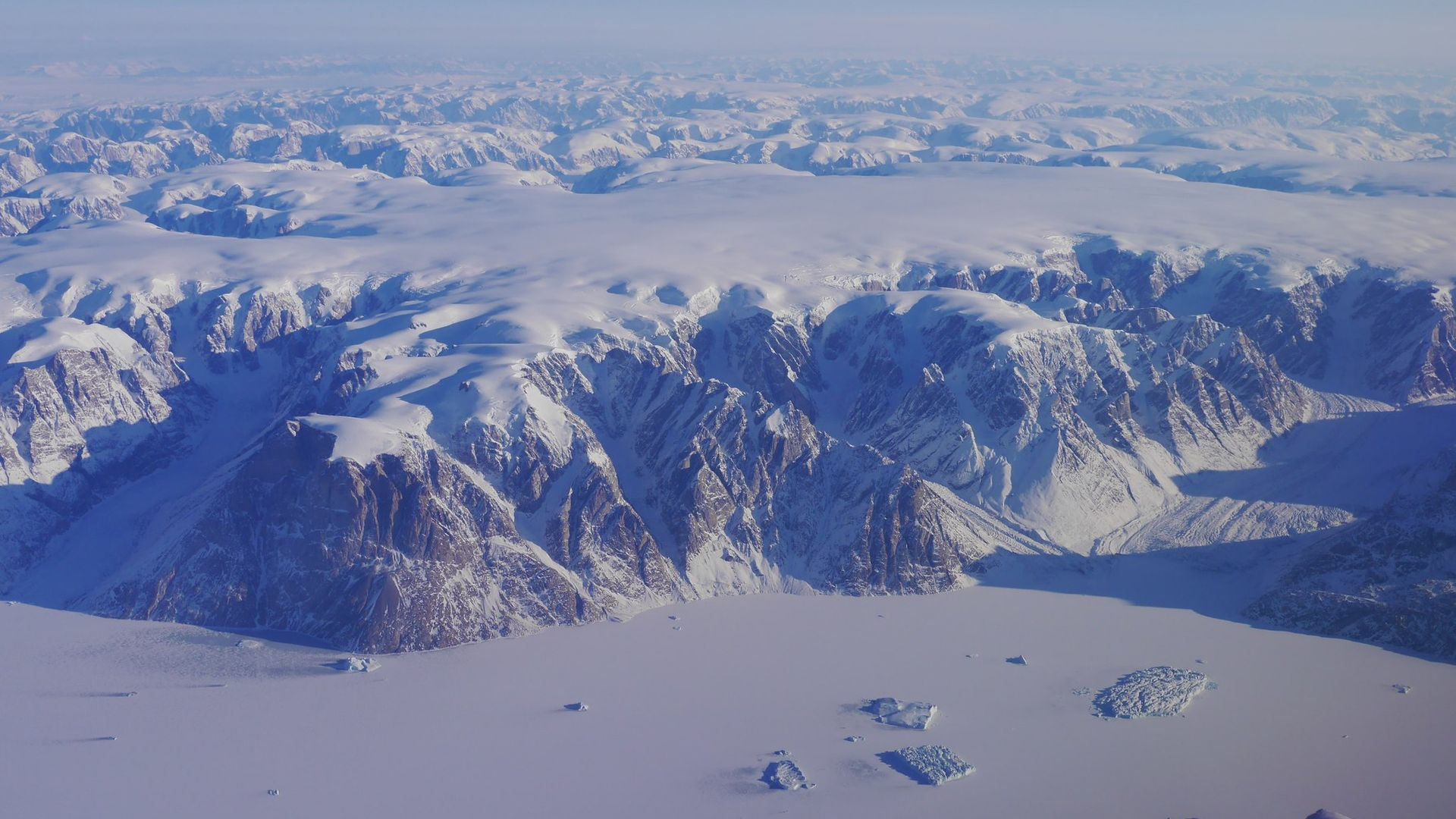 An aerial image shows a vast and mountainous ice cap in Greenland.