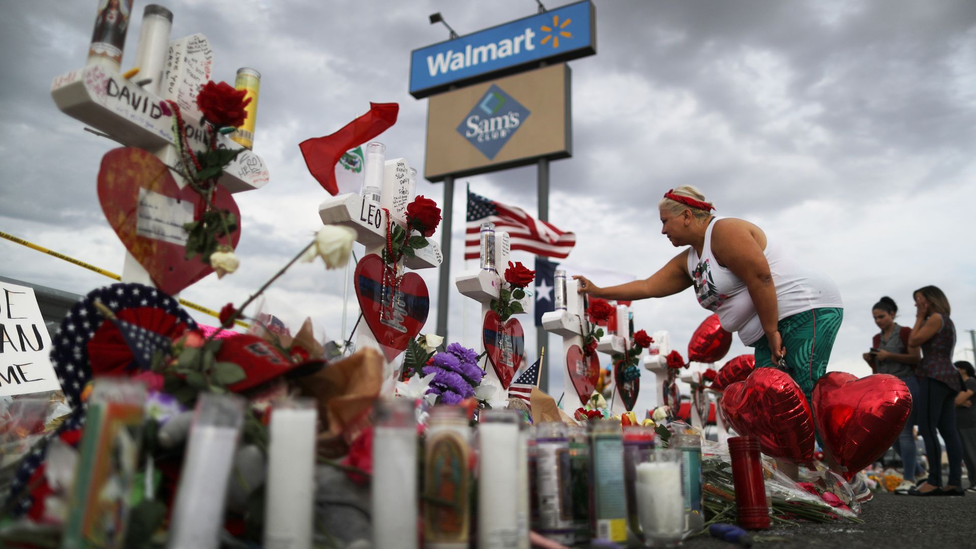 A woman touches a cross at a makeshift memorial for victims outside Walmart, near the scene of a mass shooting