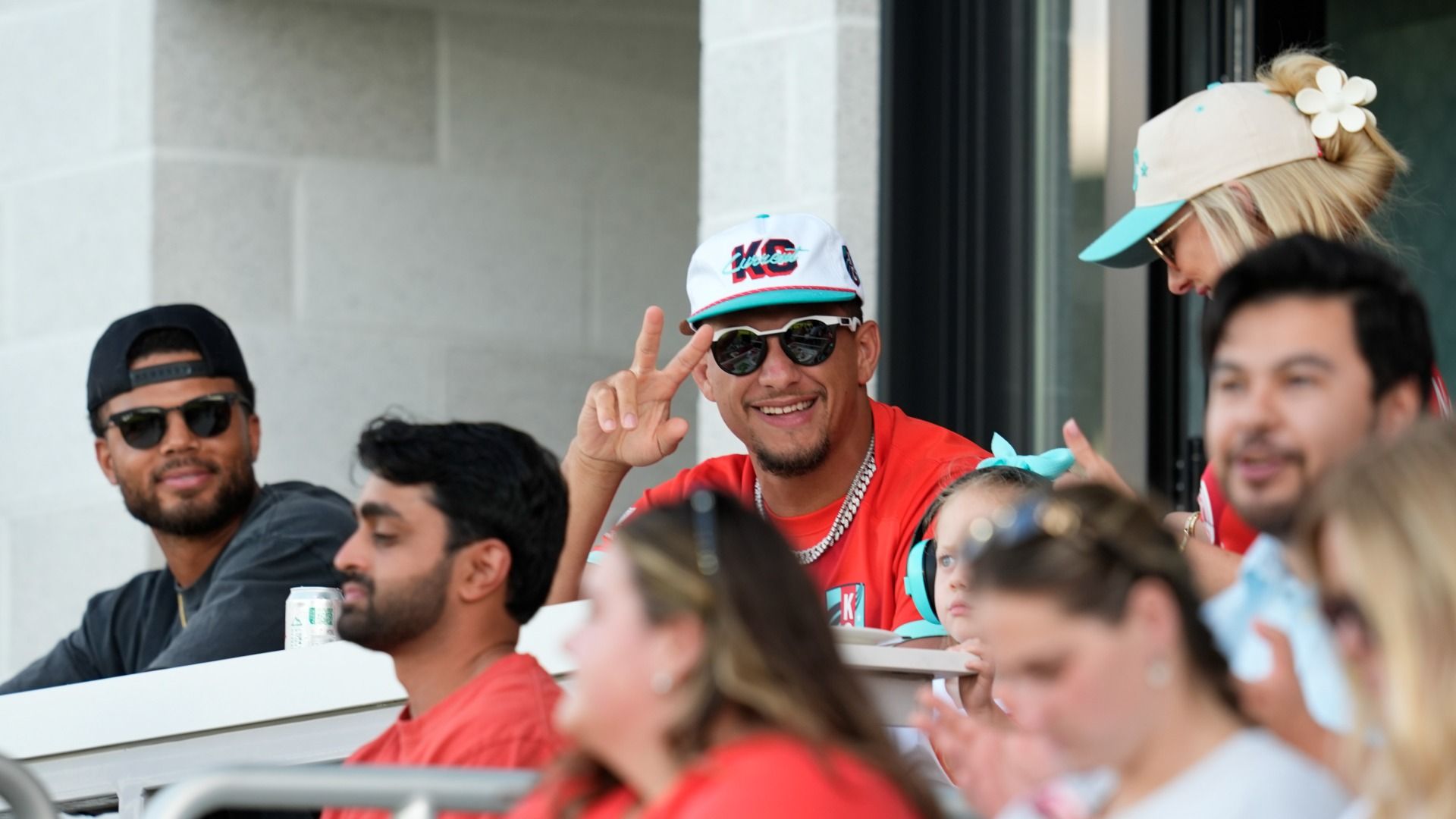 Patrick Mahomes smiles and waves to the camera at a KC Current game.