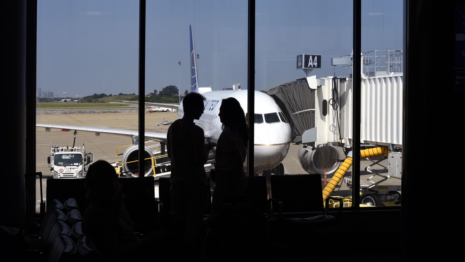 A couple silhouetted in front of a window talk in the terminal gate area before boarding a plane at Nashville International Airport