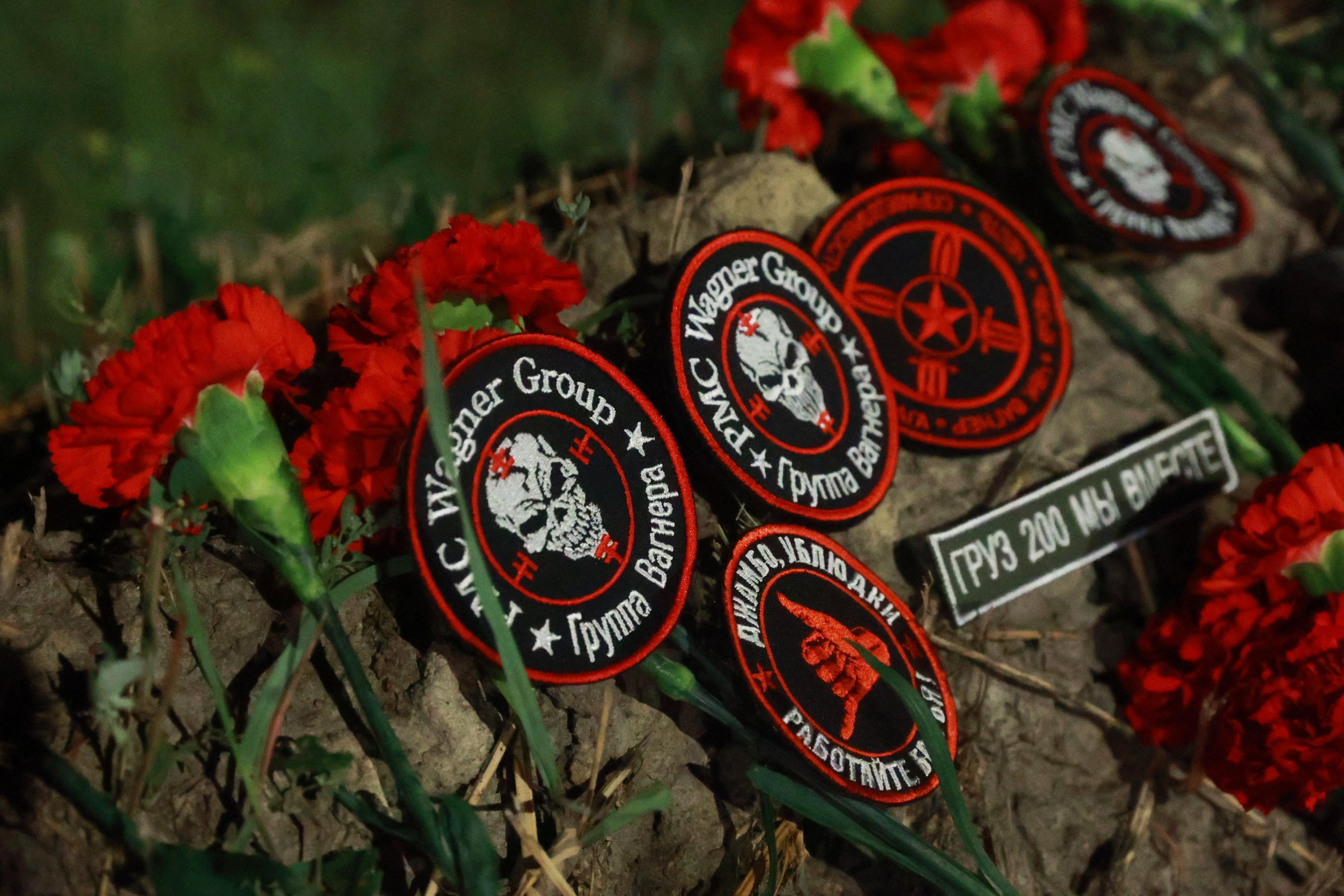 Flowers and patches bearing the logo of private mercenary group Wagner are seen at the makeshift memorial in front of the "PMC Wagner Centre" in Saint Petersburg, early on August 24, 2023. Russian state-run news agencies on August 23, 2023 said that Yevgeny Prigozhin, the head of the Wagner group that led a mutiny against Russia's army in June, was on the list of passengers of a plane that crashed near the village of Kuzhenkino in the Tver Region.