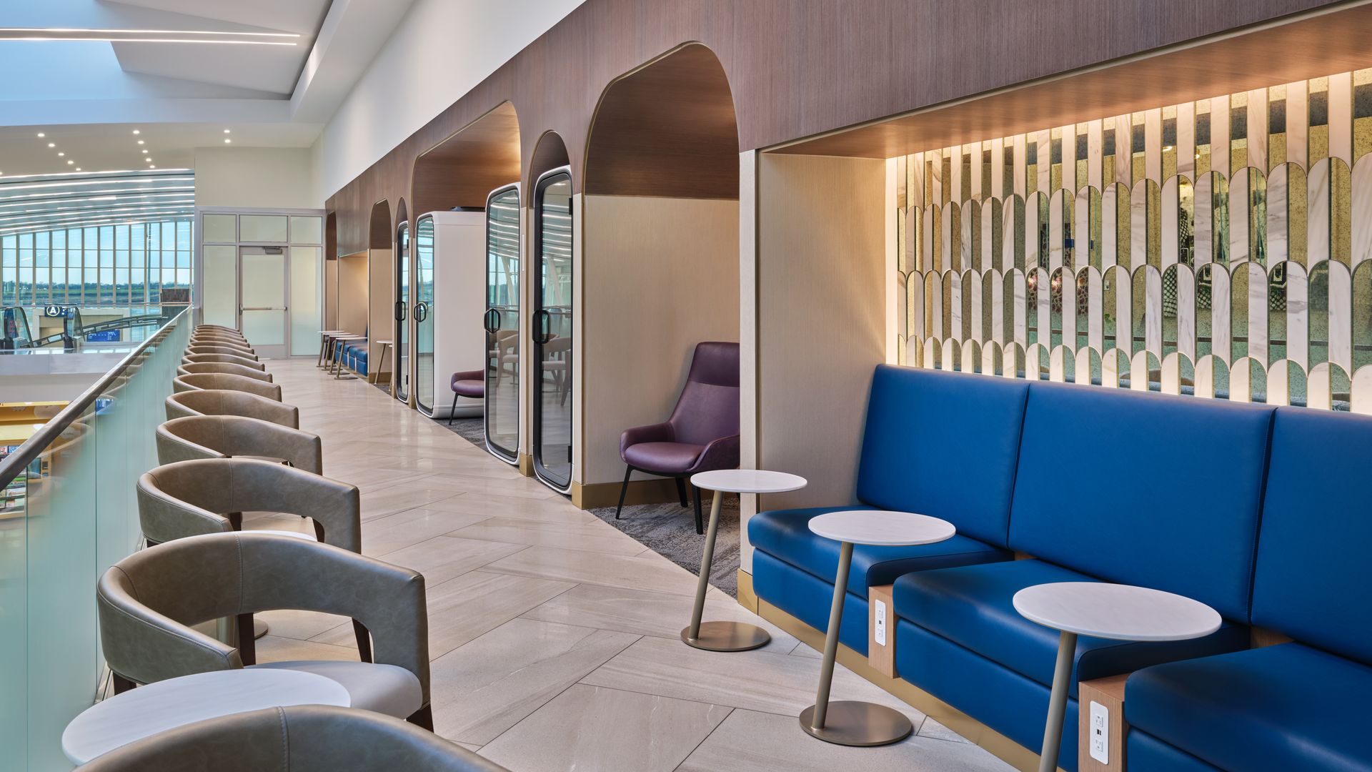 An elegant seating area of an exclusive lounge overlooking an atrium at an airport 