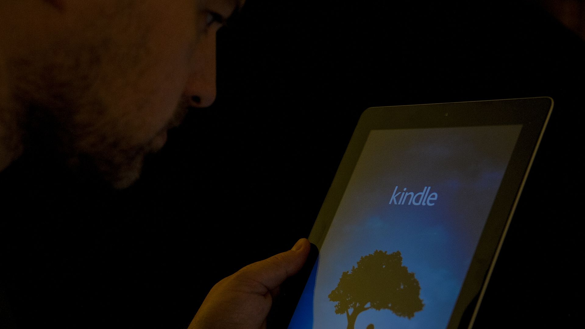 Man reading off Kindle e-reader. 