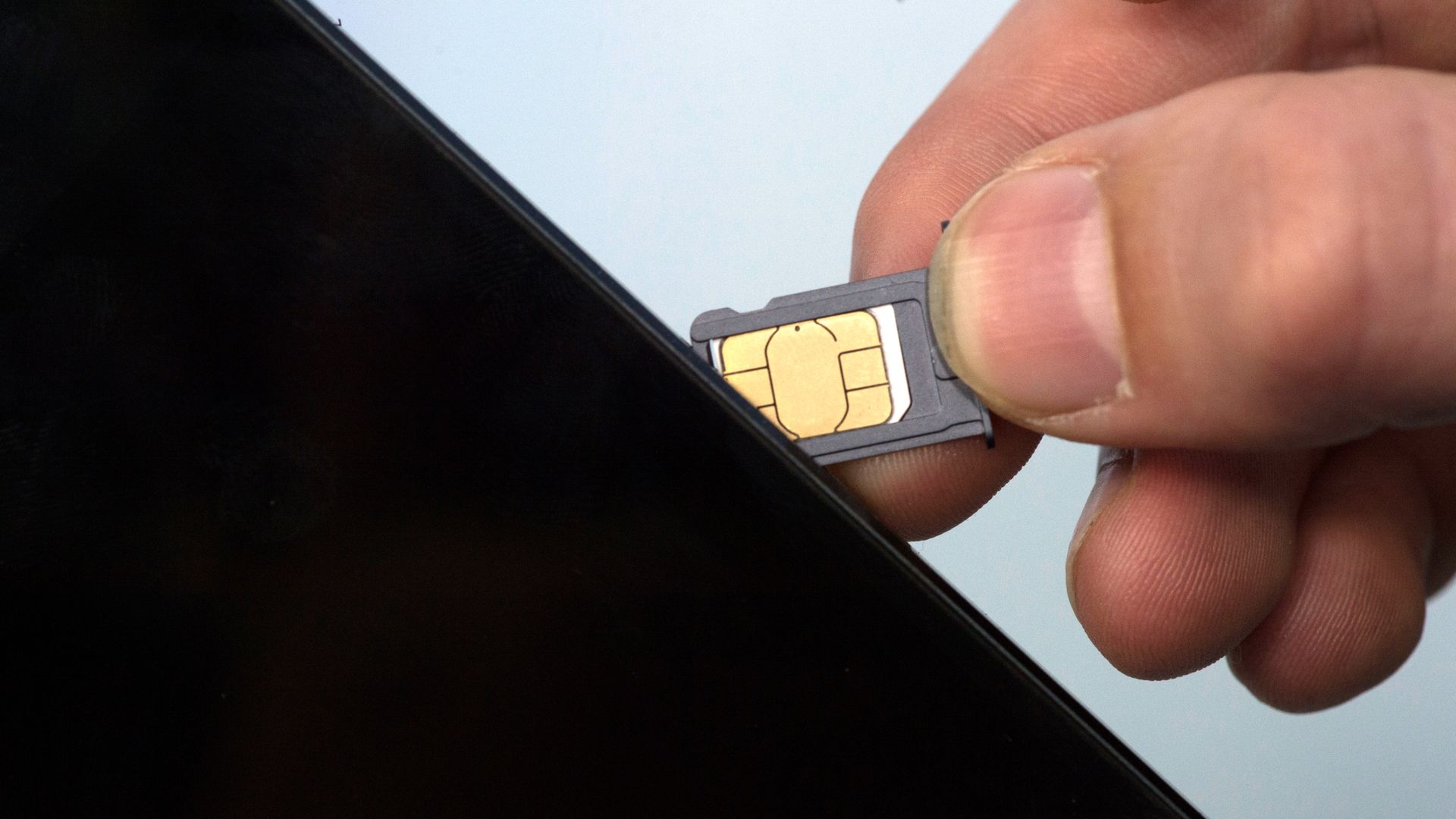 hand putting a SIM card into a phone