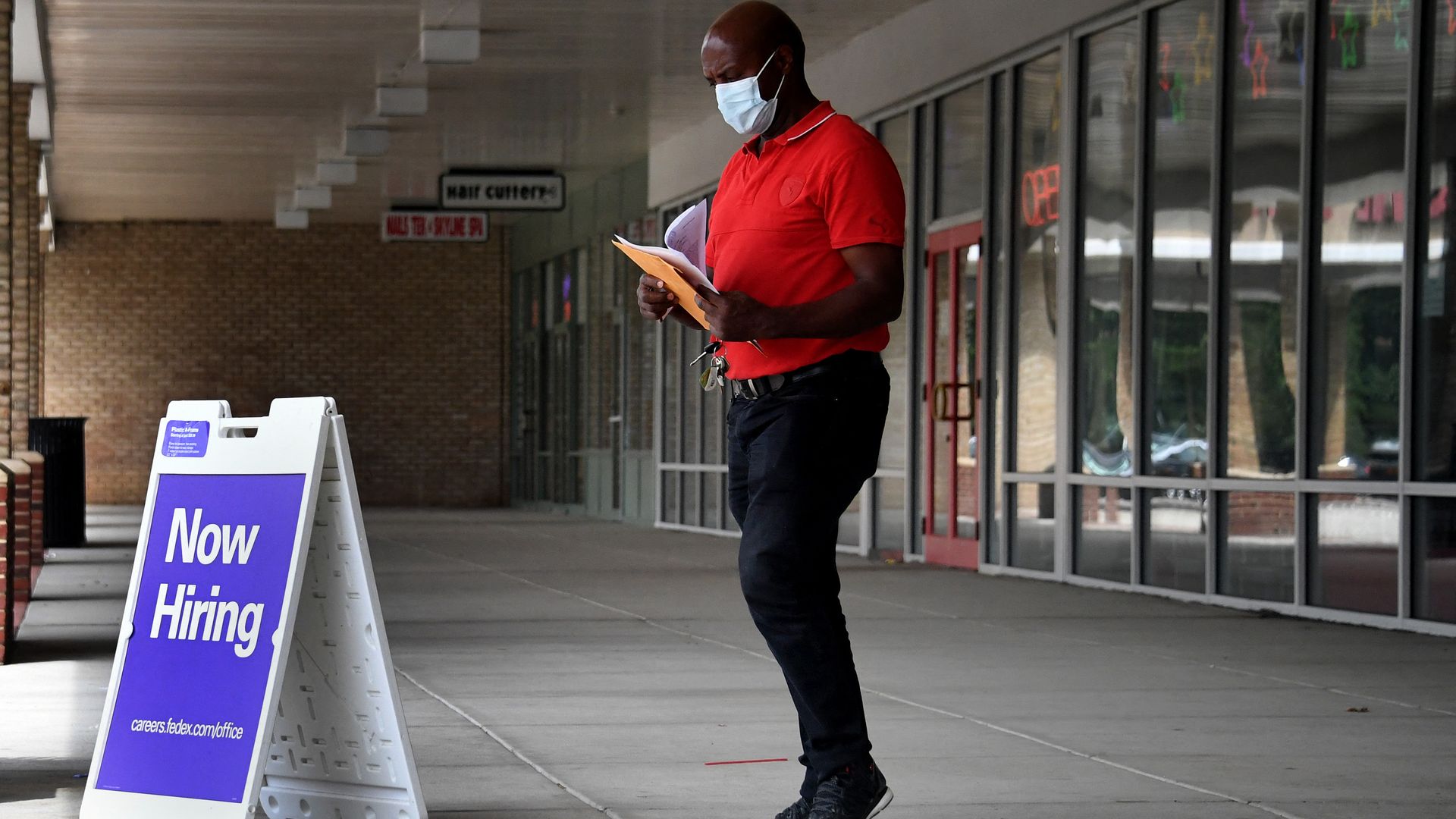 A man walks by a "Now Hiring" sign outside a store in Arlington, Va.