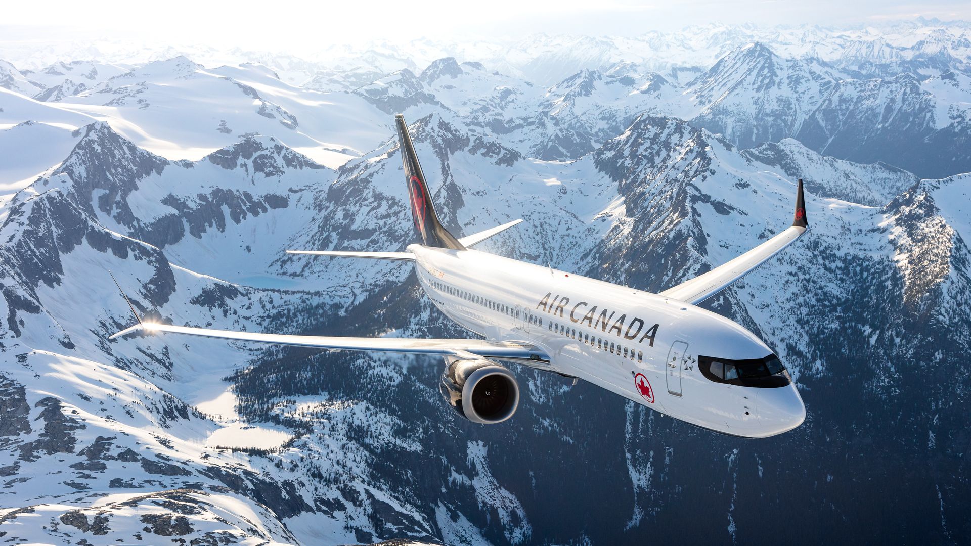 An Air Canada plane flying over snowcapped mountains