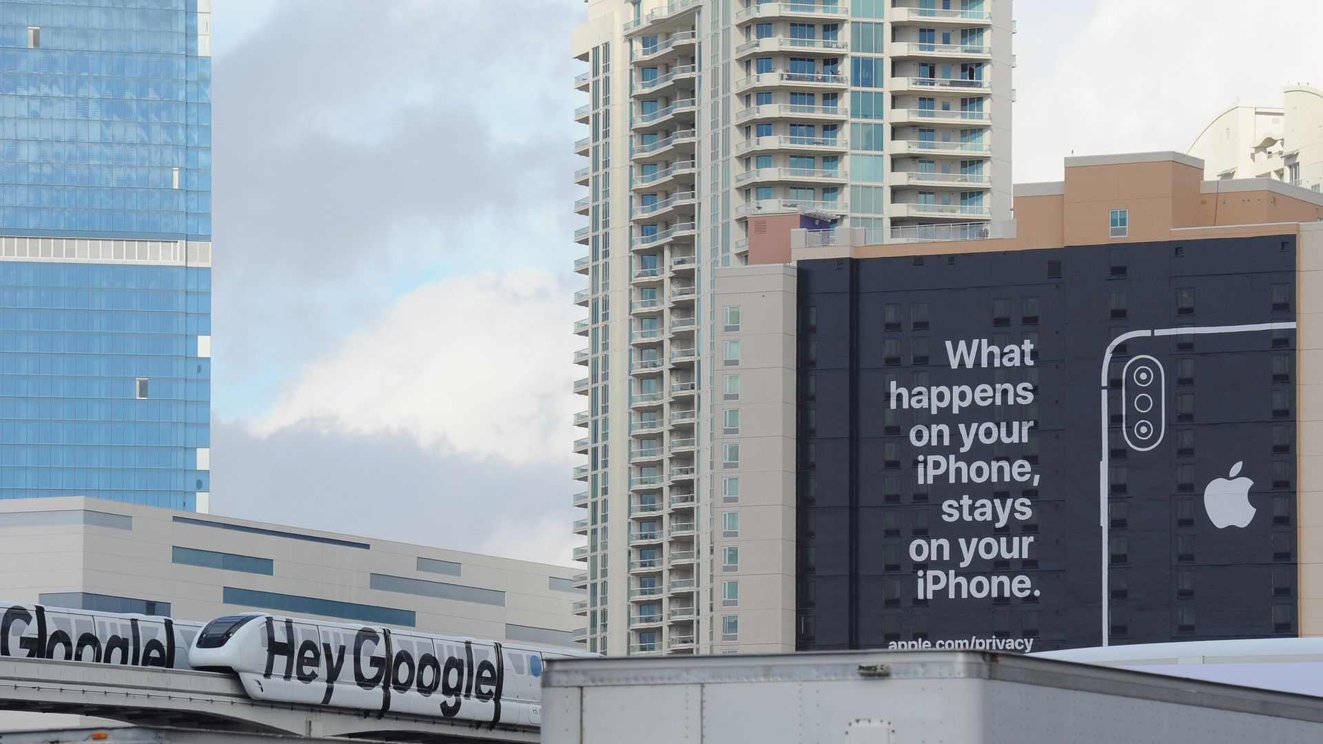 An ad that says "What happens on your iPhone, stays on your iPhone" next to a monorail that says "Hey Google"